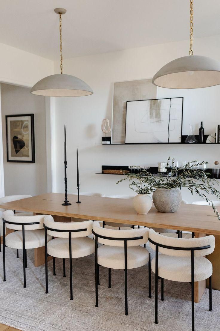 Modern minimalist dining room with curved chairs and pendant lights.