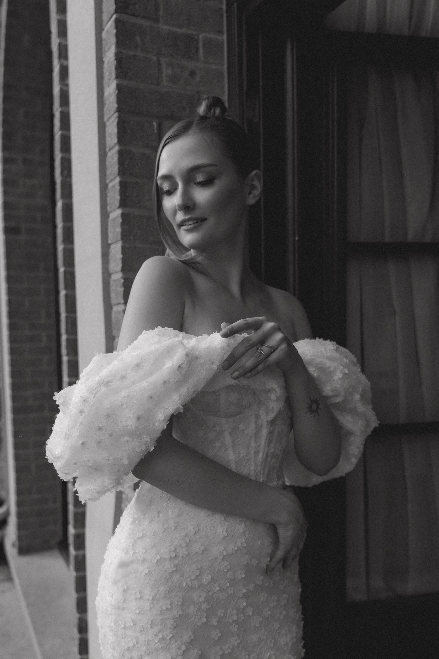 Black and white portrait of bride in off-shoulder textured wedding dress.