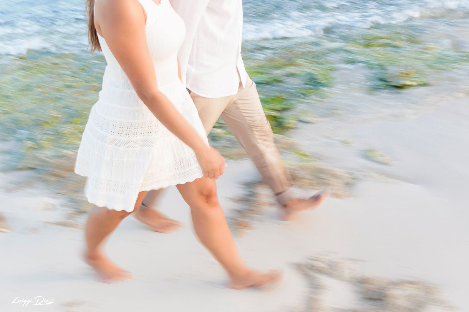 Bare feet walking along a sandy beach shoreline with gentle waves in soft focus.