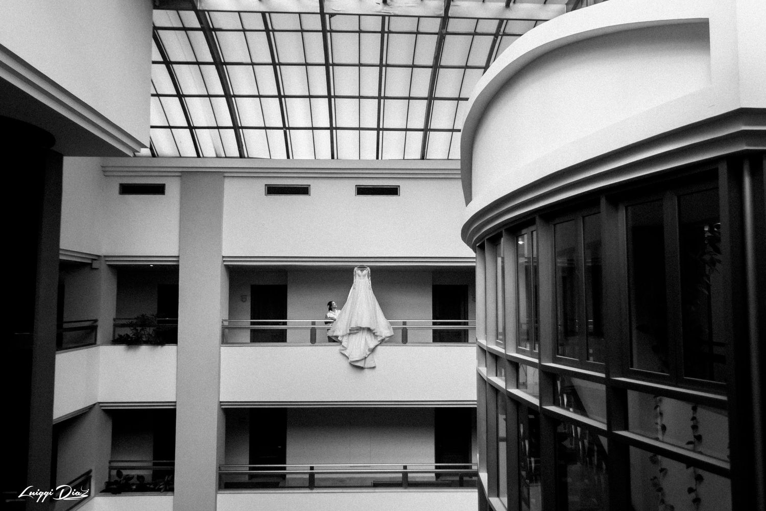 Black and white architectural photo of wedding dress displayed in modern building atrium.