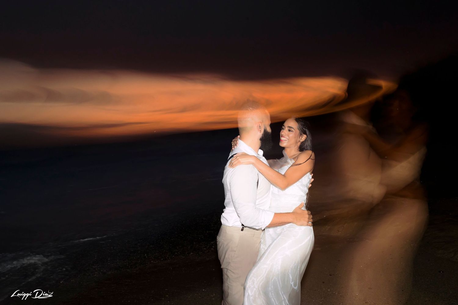 Couple dancing on beach at sunset with motion blur creating ethereal effect.