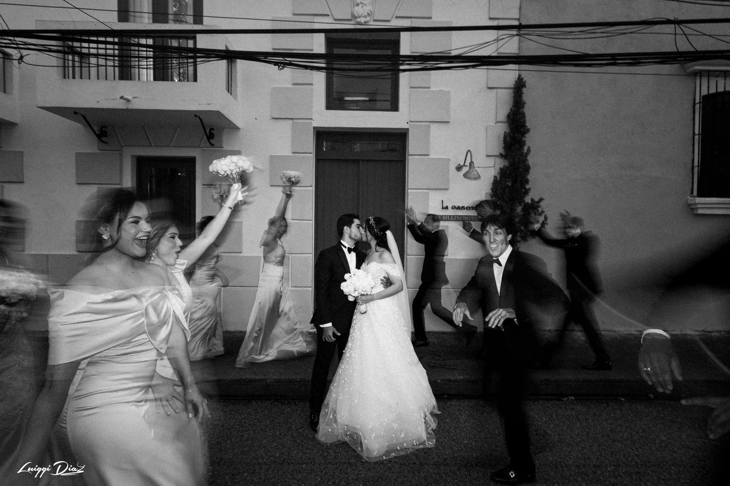 A wedding party dances and celebrates together in a black and white photo.