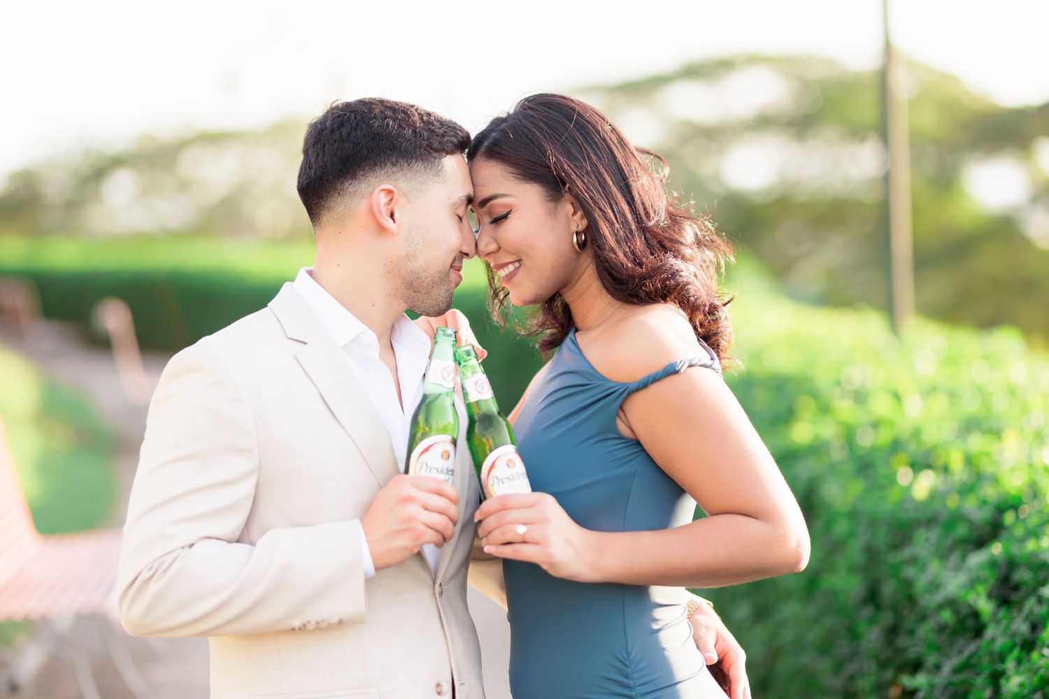Romantic couple sharing intimate moment while holding champagne glasses in garden setting.