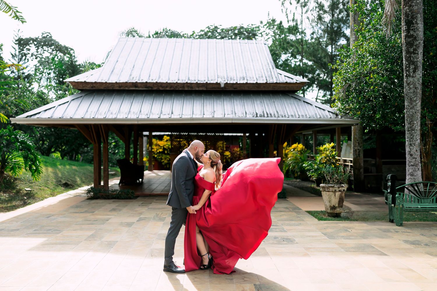 A romantic moment captured under an Asian-style pavilion with a flowing red dress.