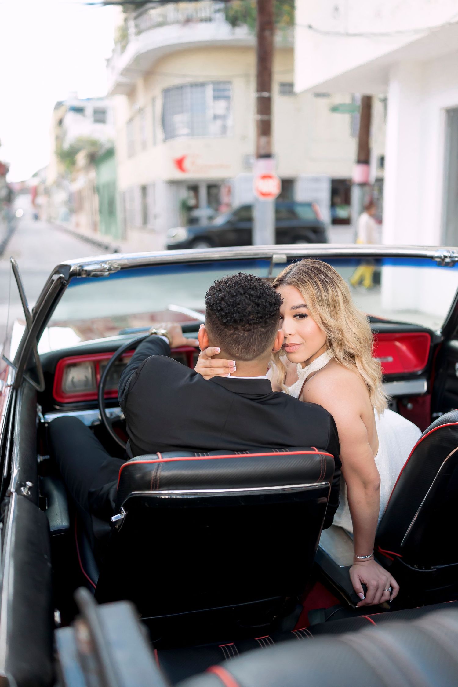 Romantic couple sitting in vintage convertible car during sunset.