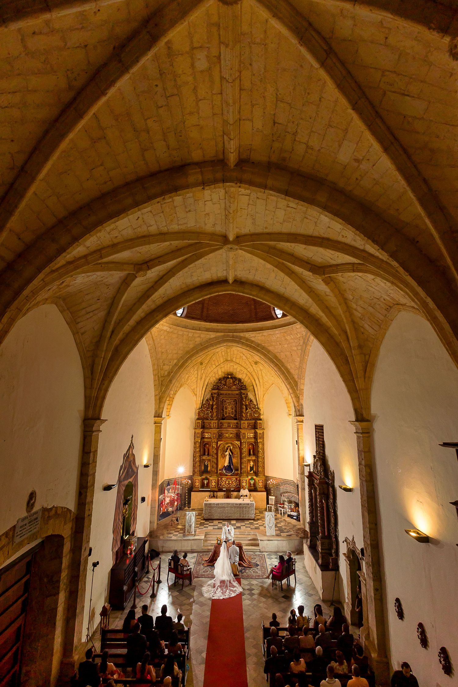 Wedding ceremony in historic cathedral with vaulted ceilings and golden altar.