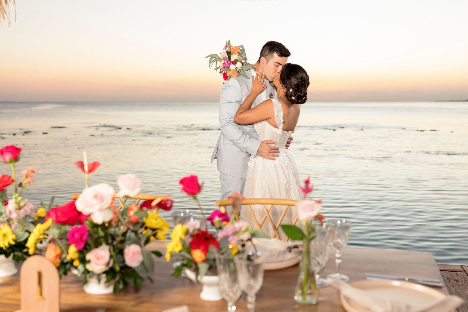 A romantic sunset wedding scene with floral decorations by the ocean.