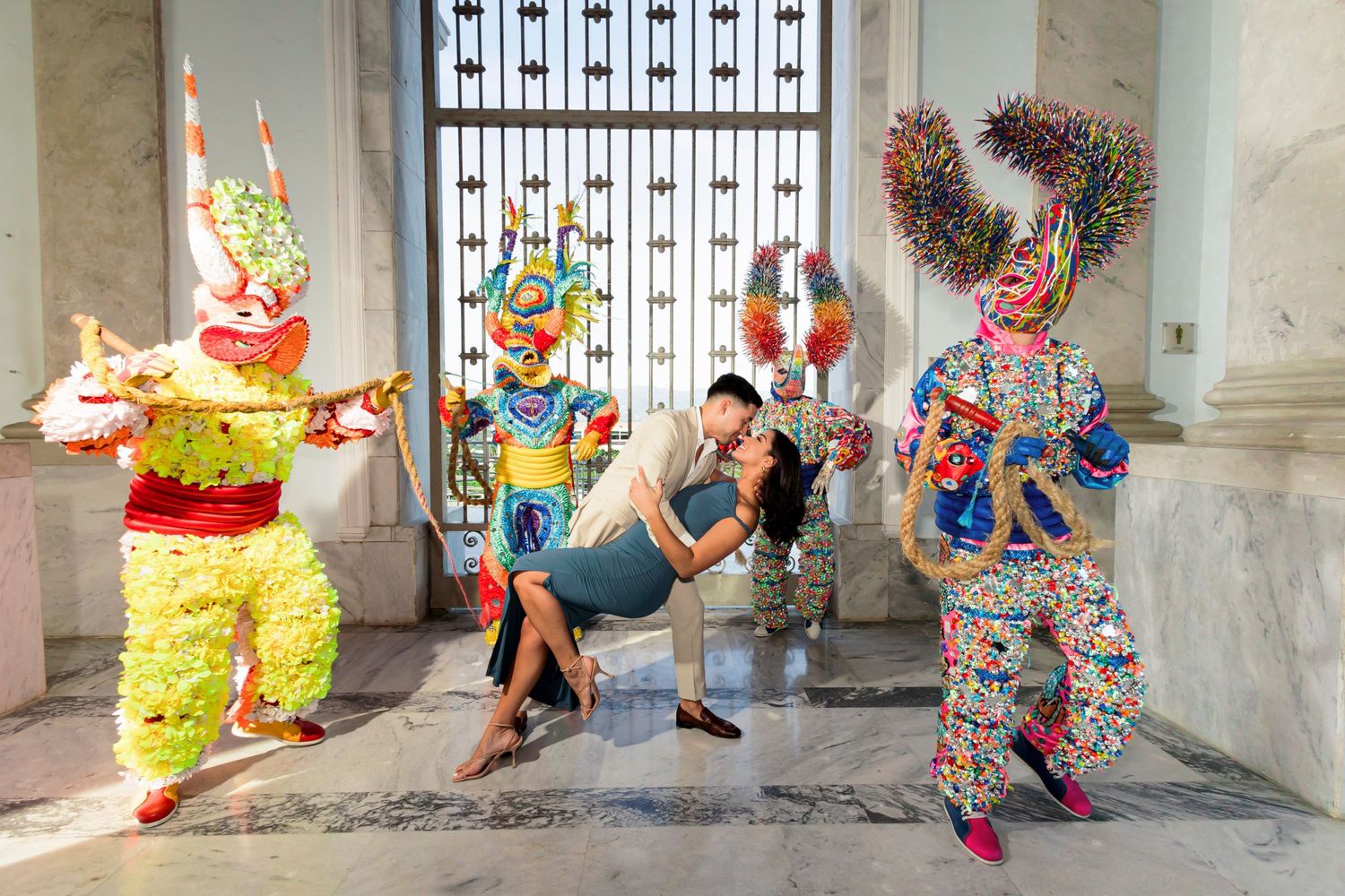 Fun engagement photo with couple posing among colorful traditional festival characters.