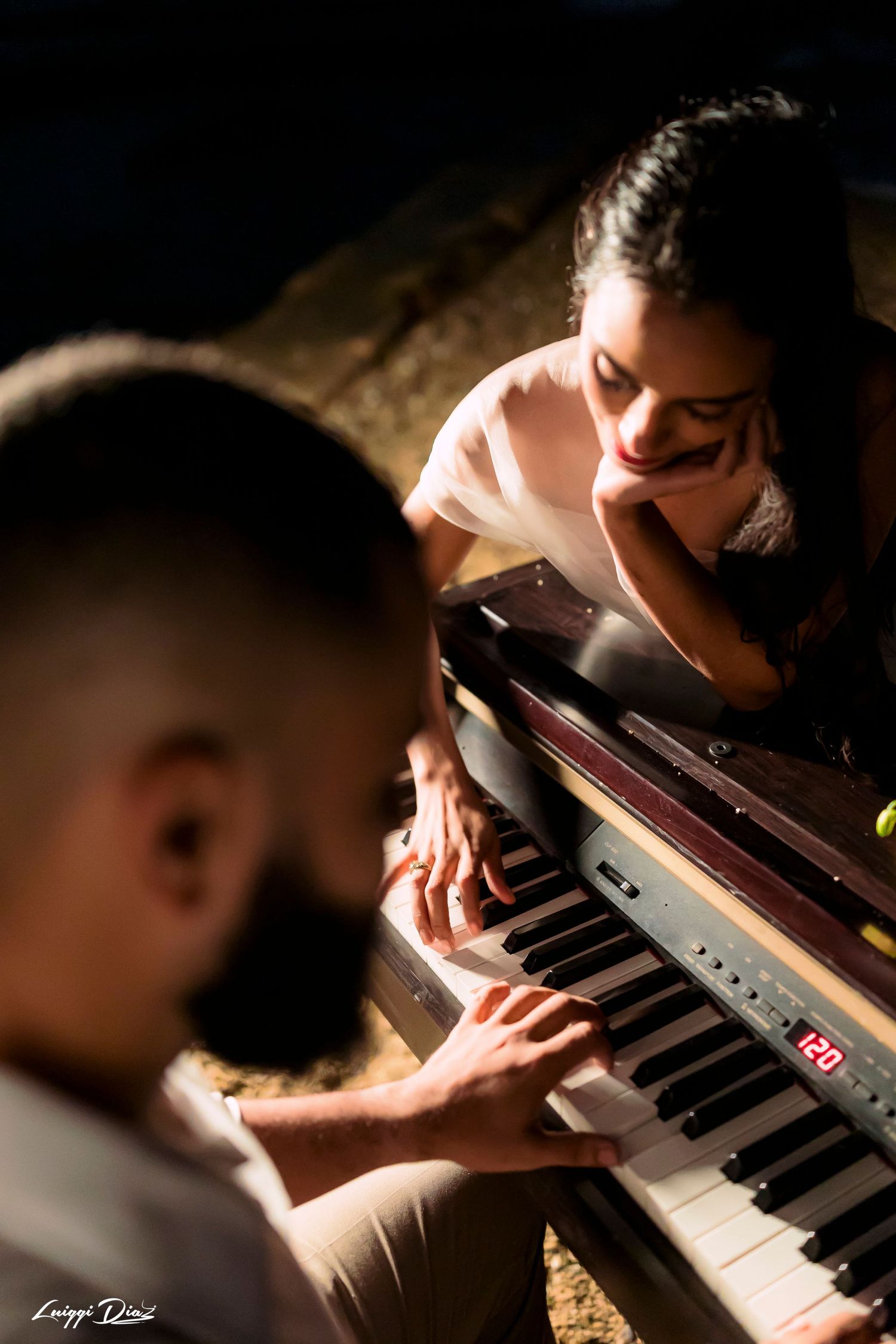 Intimate moment captured at piano with dramatic lighting and shallow depth of field.
