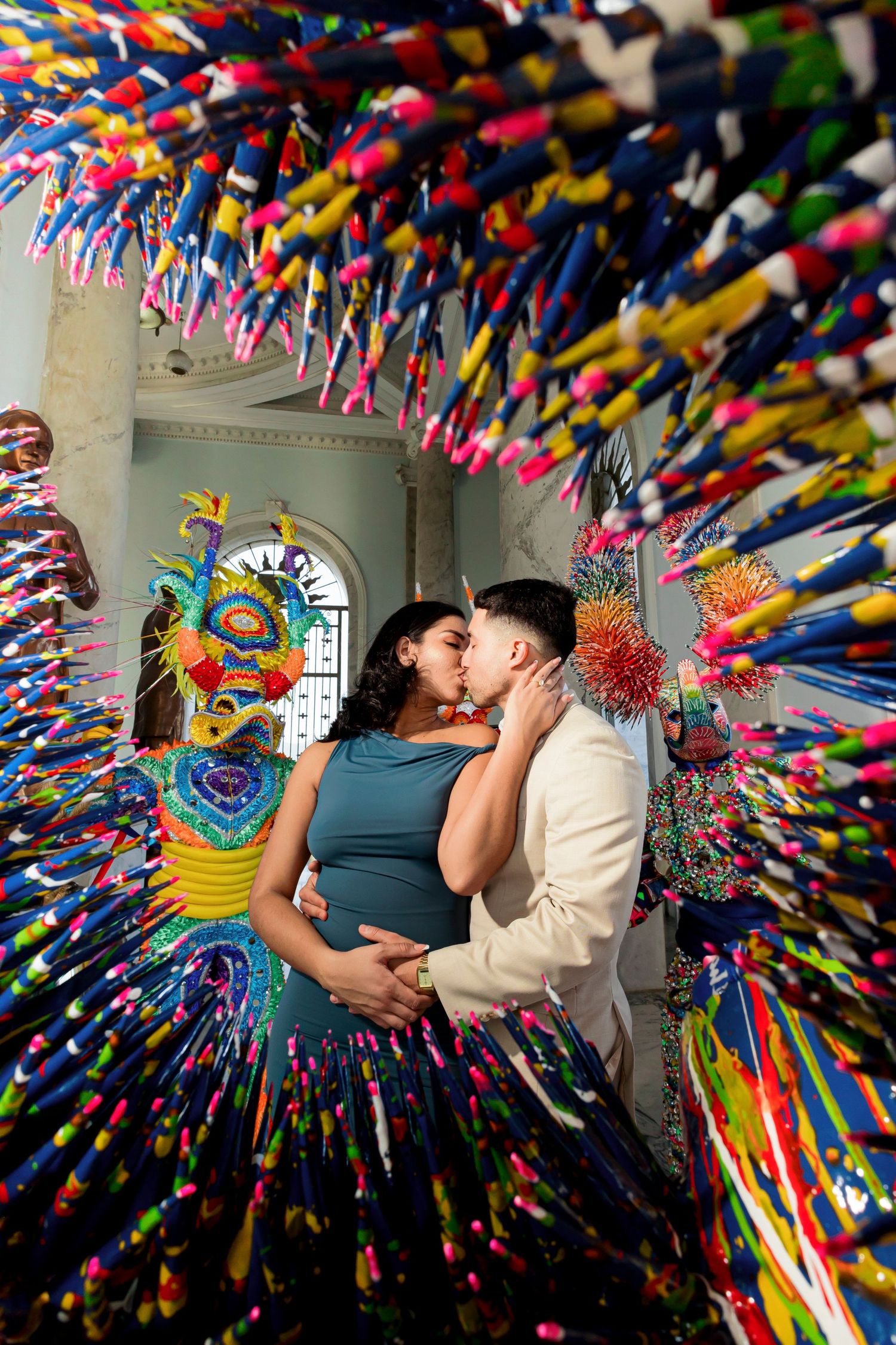 Artistic engagement photo with couple surrounded by vibrant rainbow streamer art installation.