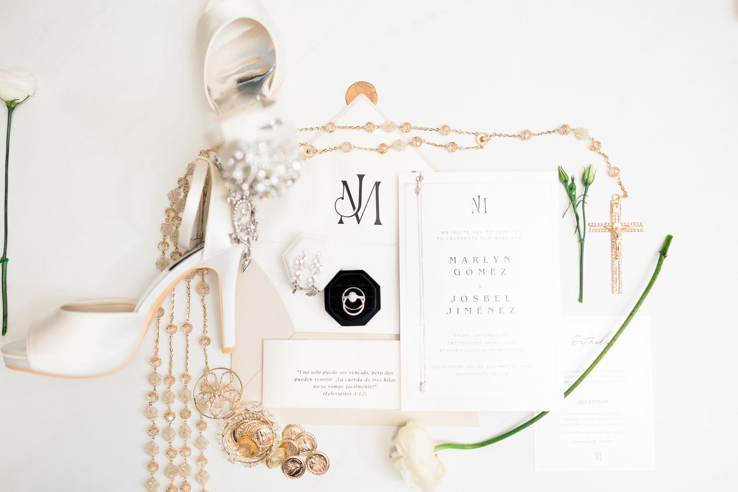 Wedding stationery flat lay with invitation suite, jewelry and delicate styling elements.