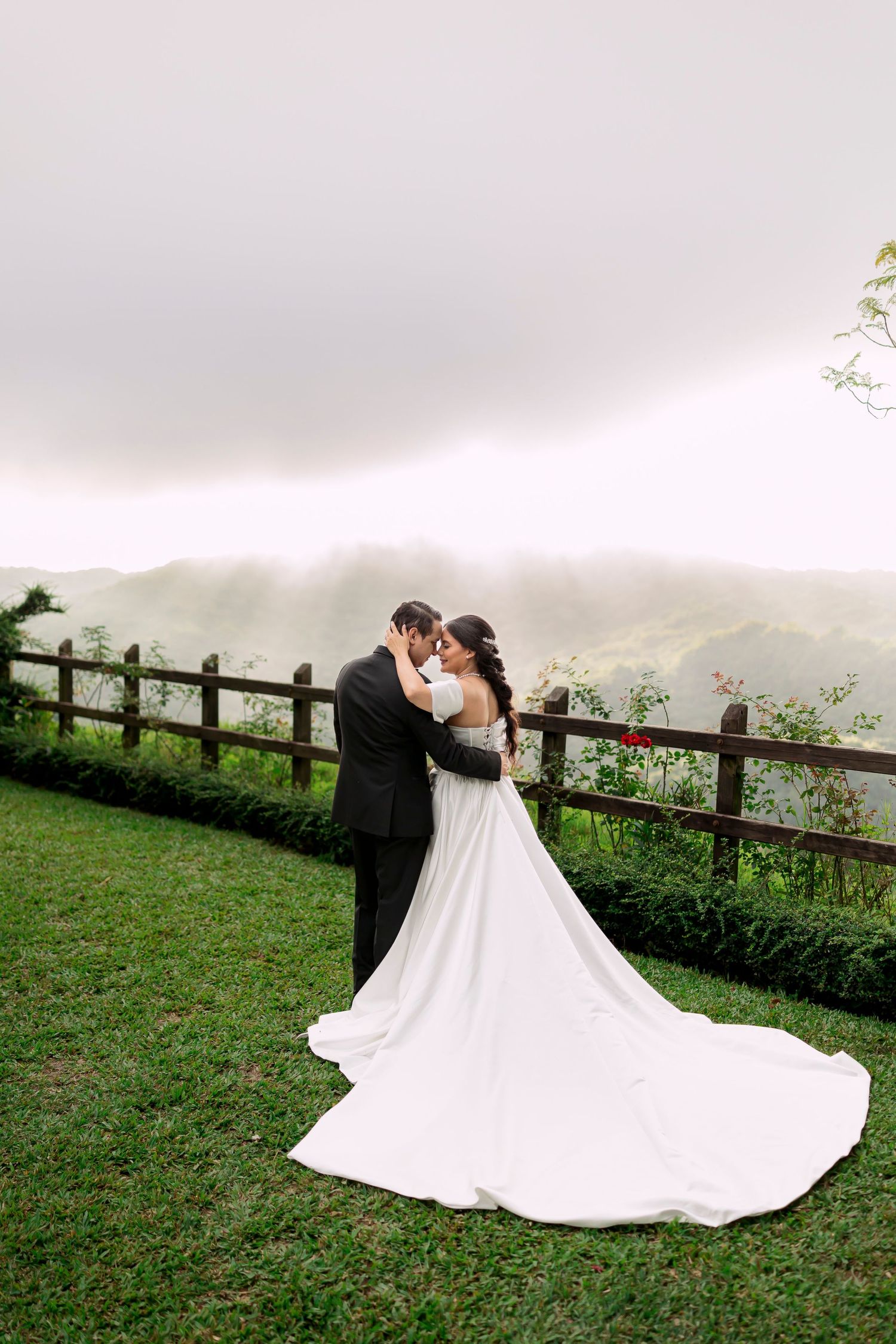 A romantic wedding portrait against a misty mountain backdrop with a beautiful flowing white gown.