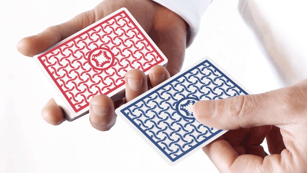 Close-up of hands holding red and blue patterned playing cards.