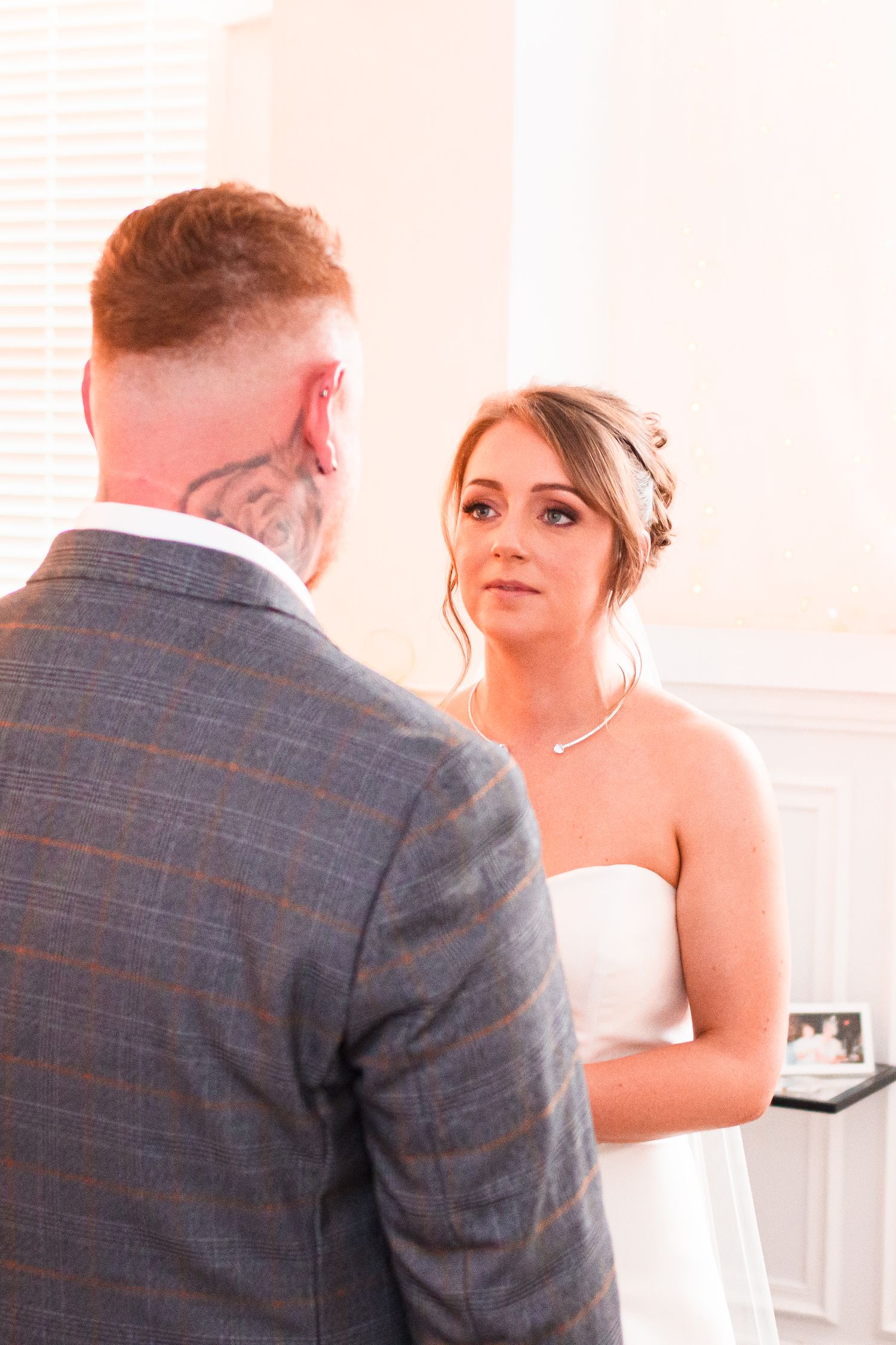 A couple shares an intimate moment during their wedding ceremony in a light-filled room.