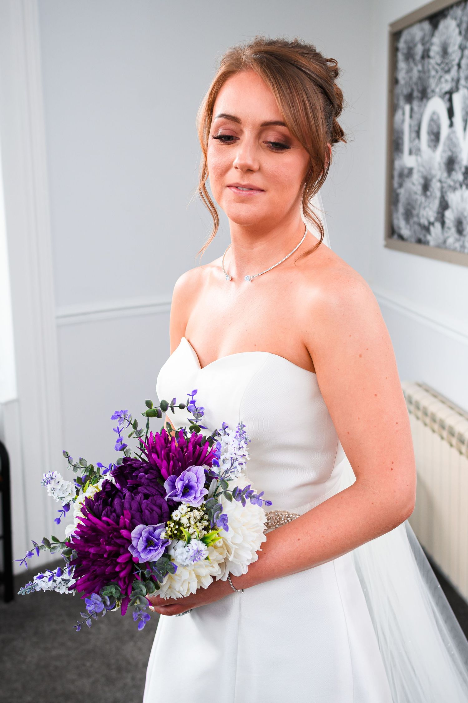 Elegant bouquet featuring vibrant purple and white flowers held against a classic white wedding gown.