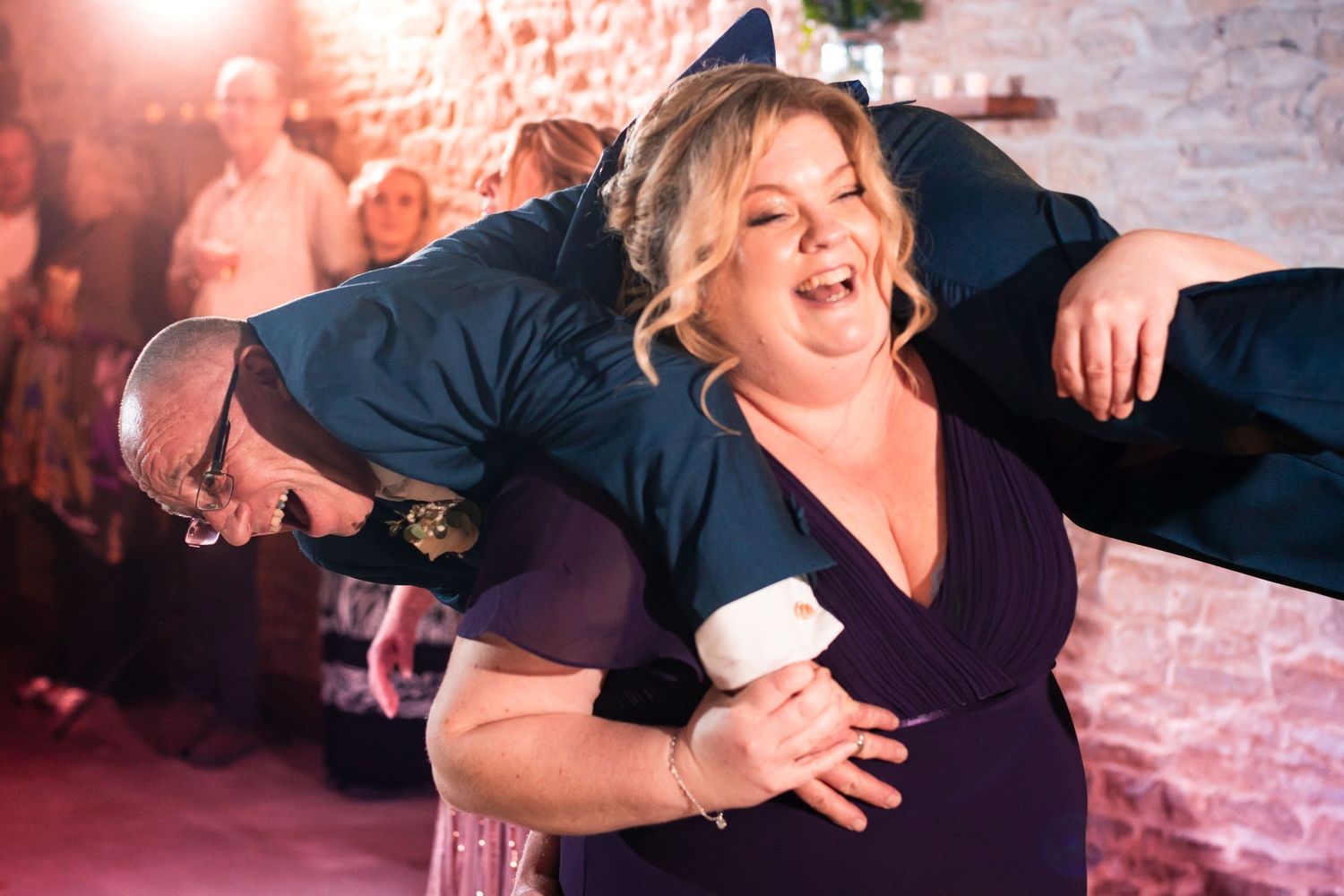 Dancers share a lively moment on the dance floor with brick walls and warm lighting in the background.