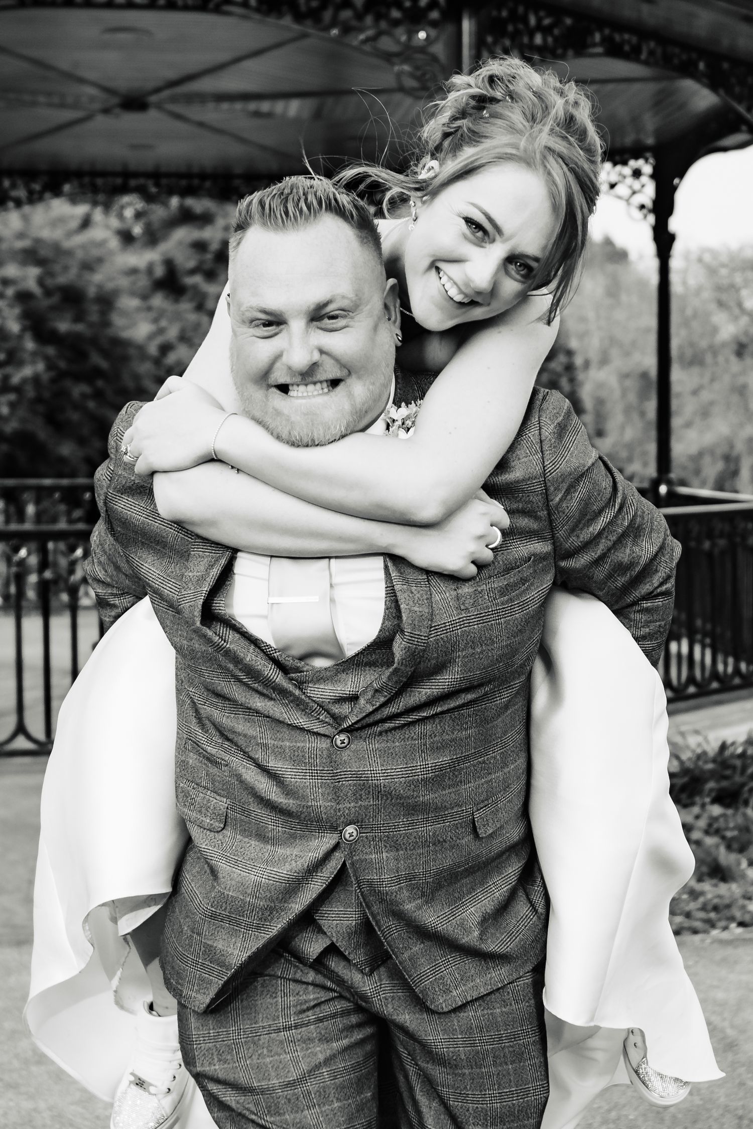 Black and white portrait of newlyweds sharing a joyful piggyback moment.