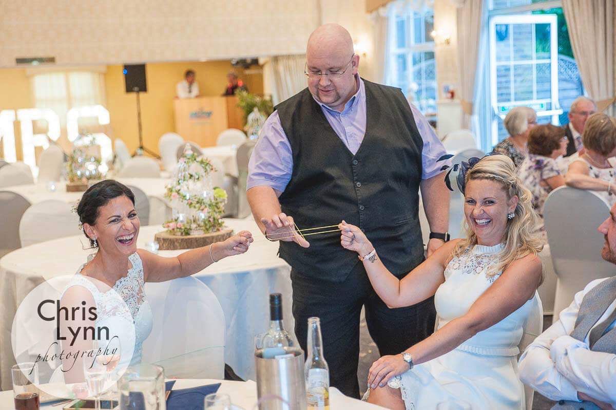 Wedding entertainment with magician performing card tricks for delighted guests.