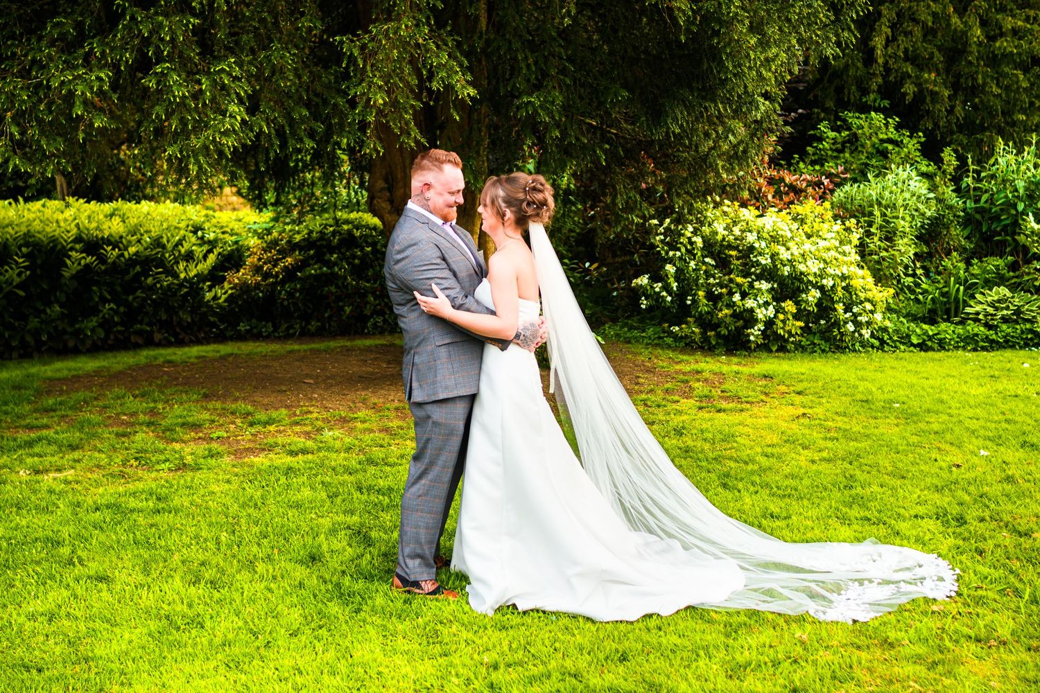 A couple sharing a romantic moment in an elegant garden setting on their wedding day.