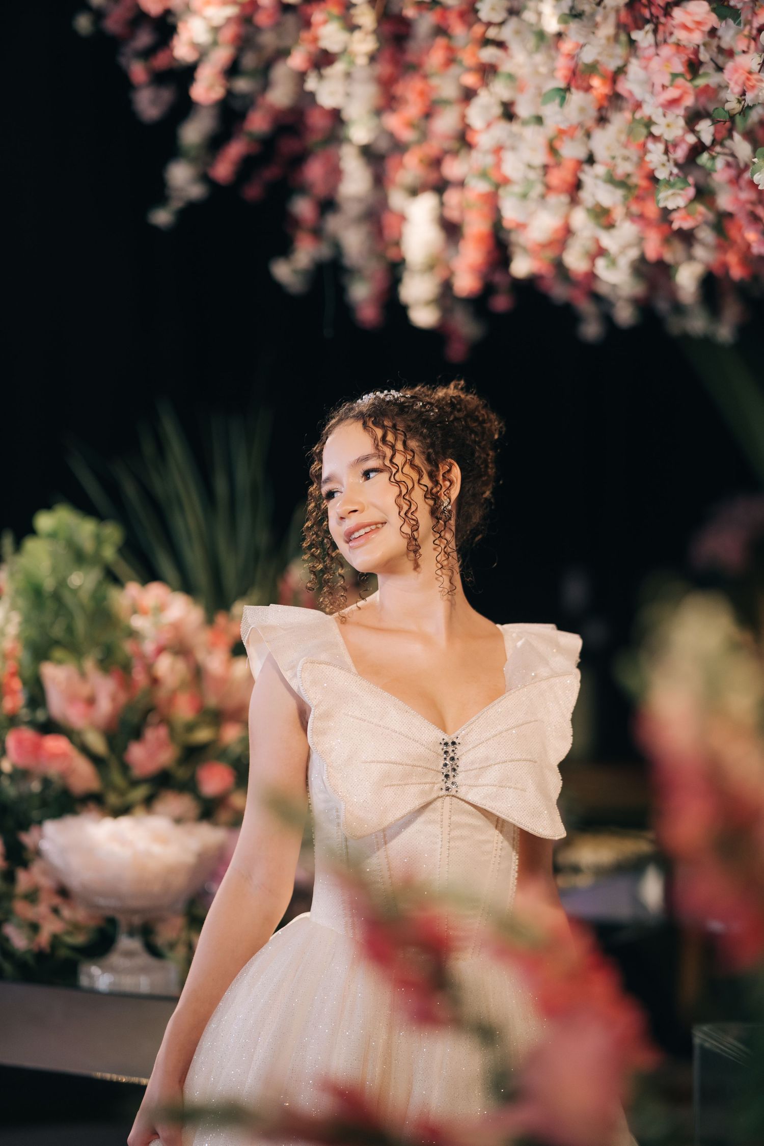 A dreamy bridal portrait under pink floral decorations with soft lighting.