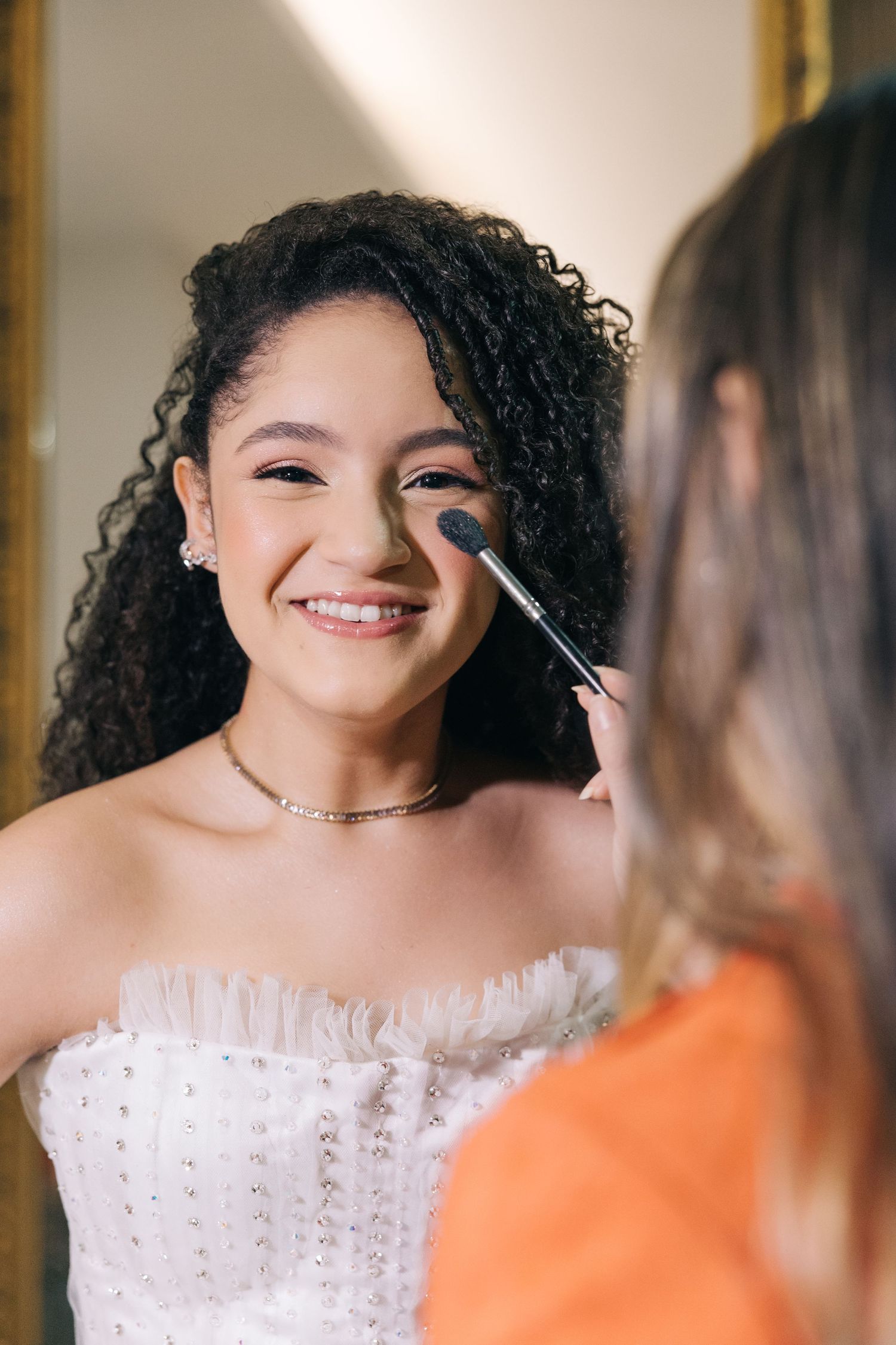 A candid moment of makeup application showing a joyful expression in the mirror.