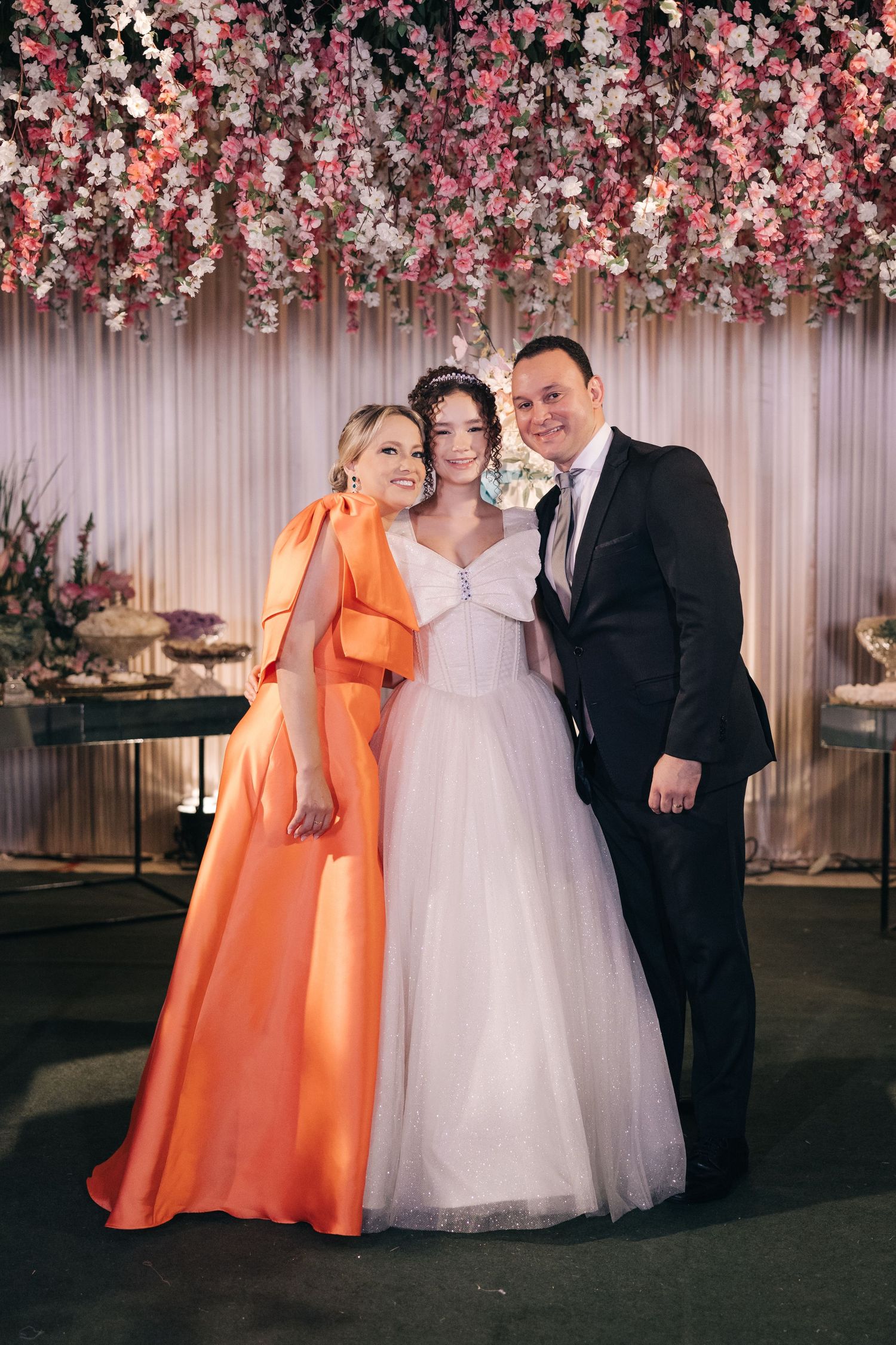 Wedding celebration under stunning pink floral ceiling installation with formal attire.