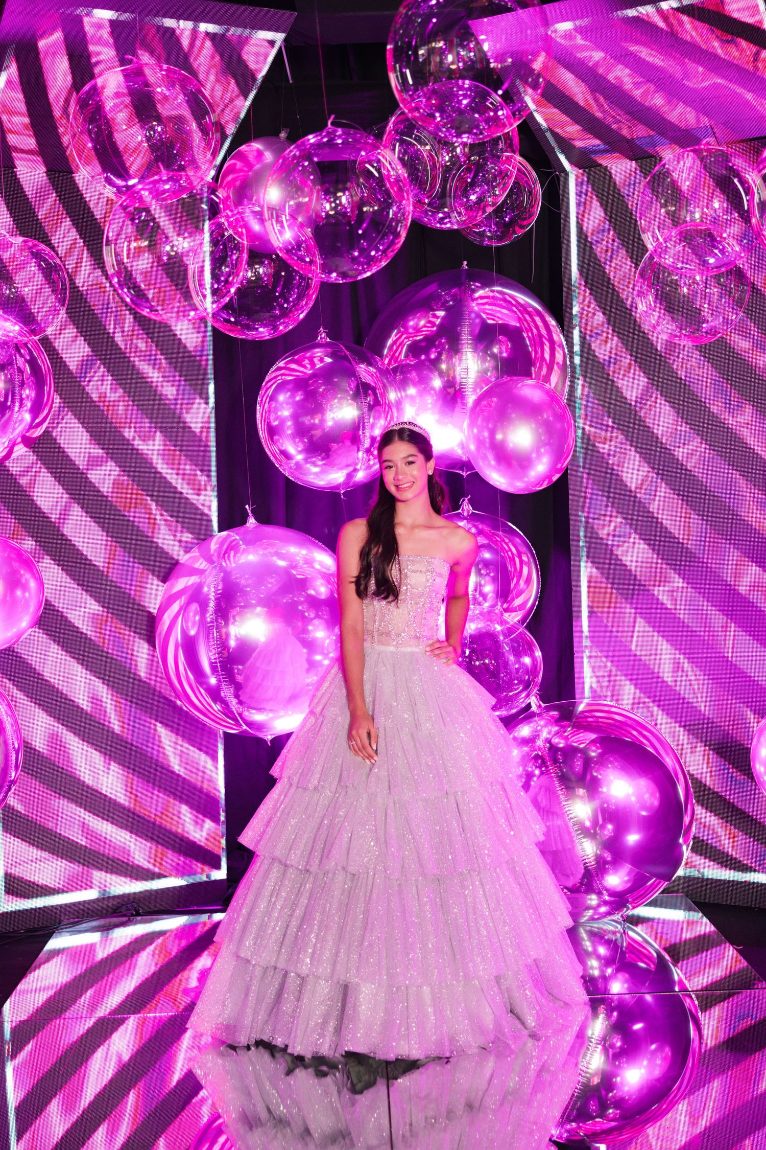 Dreamy ballgown portrait with purple balloon installations and geometric lighting effects.