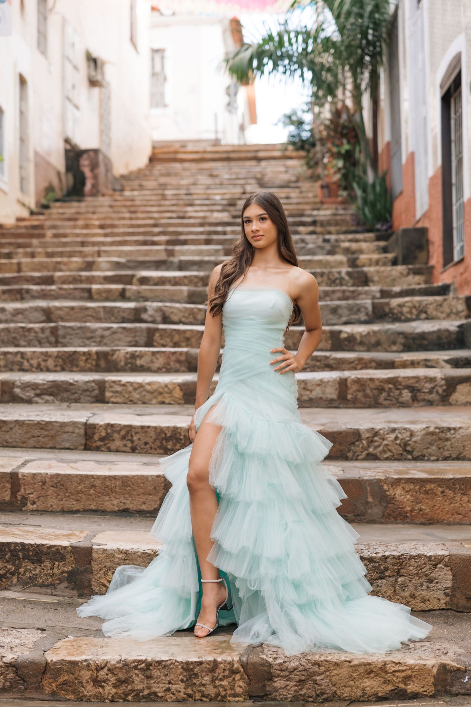 Elegant mint tulle gown with tiered ruffles photographed on rustic stone steps in a charming European setting.