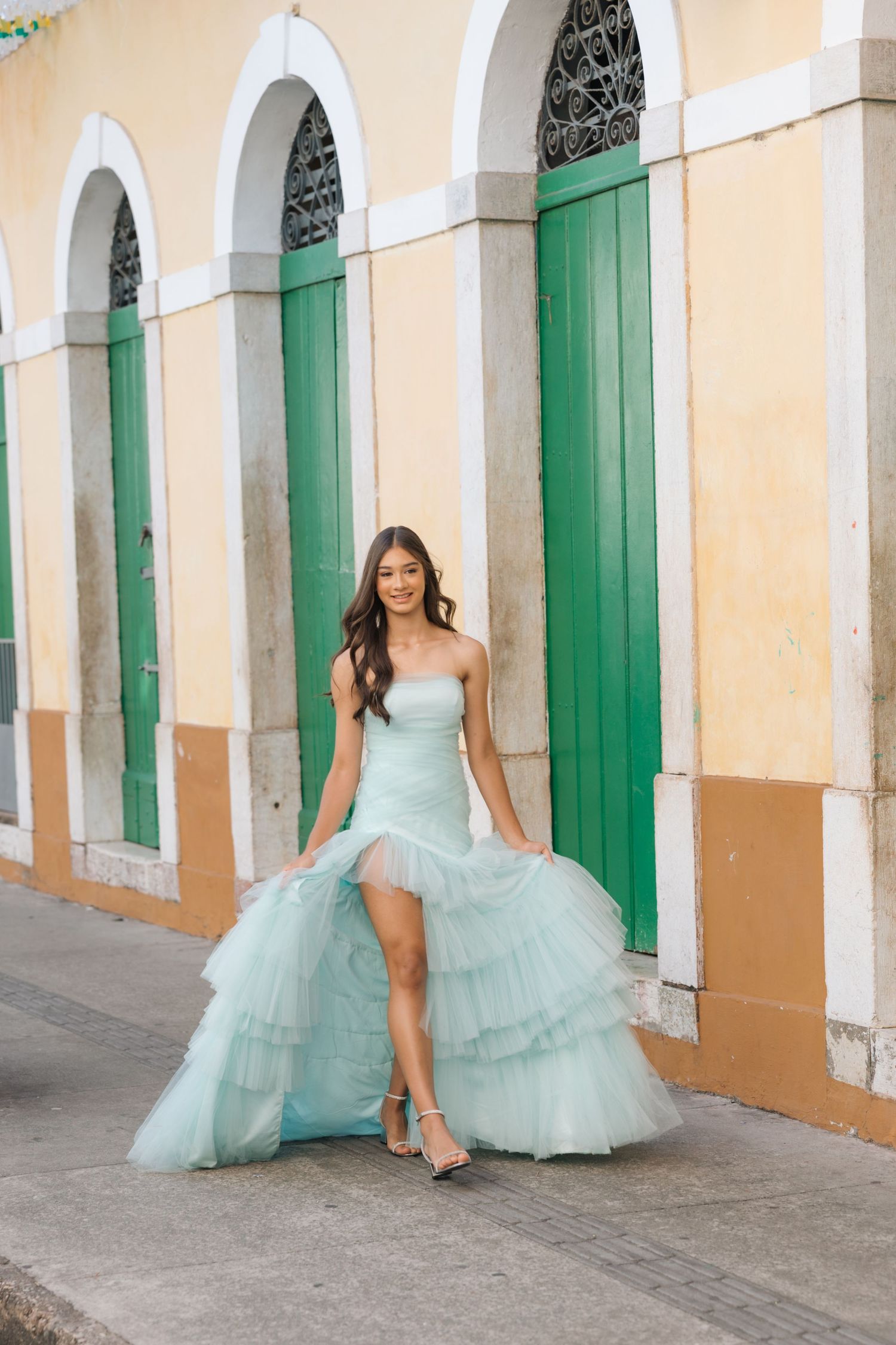 A light blue tulle gown with ruffled tiers stands out against green colonial doors and peach-colored walls.