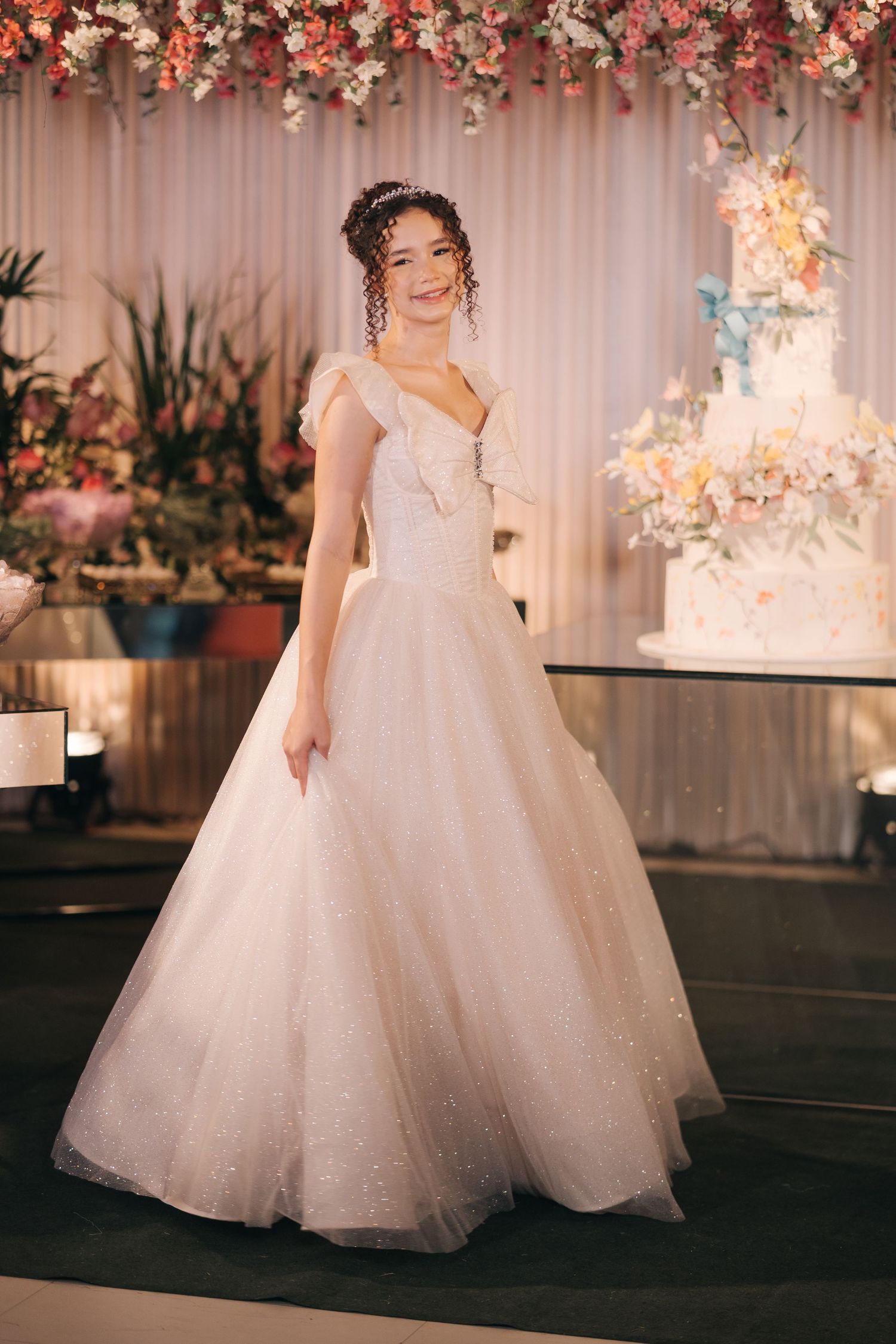 Stunning white ball gown with sparkle details photographed next to an elegant wedding cake and floral arrangements.