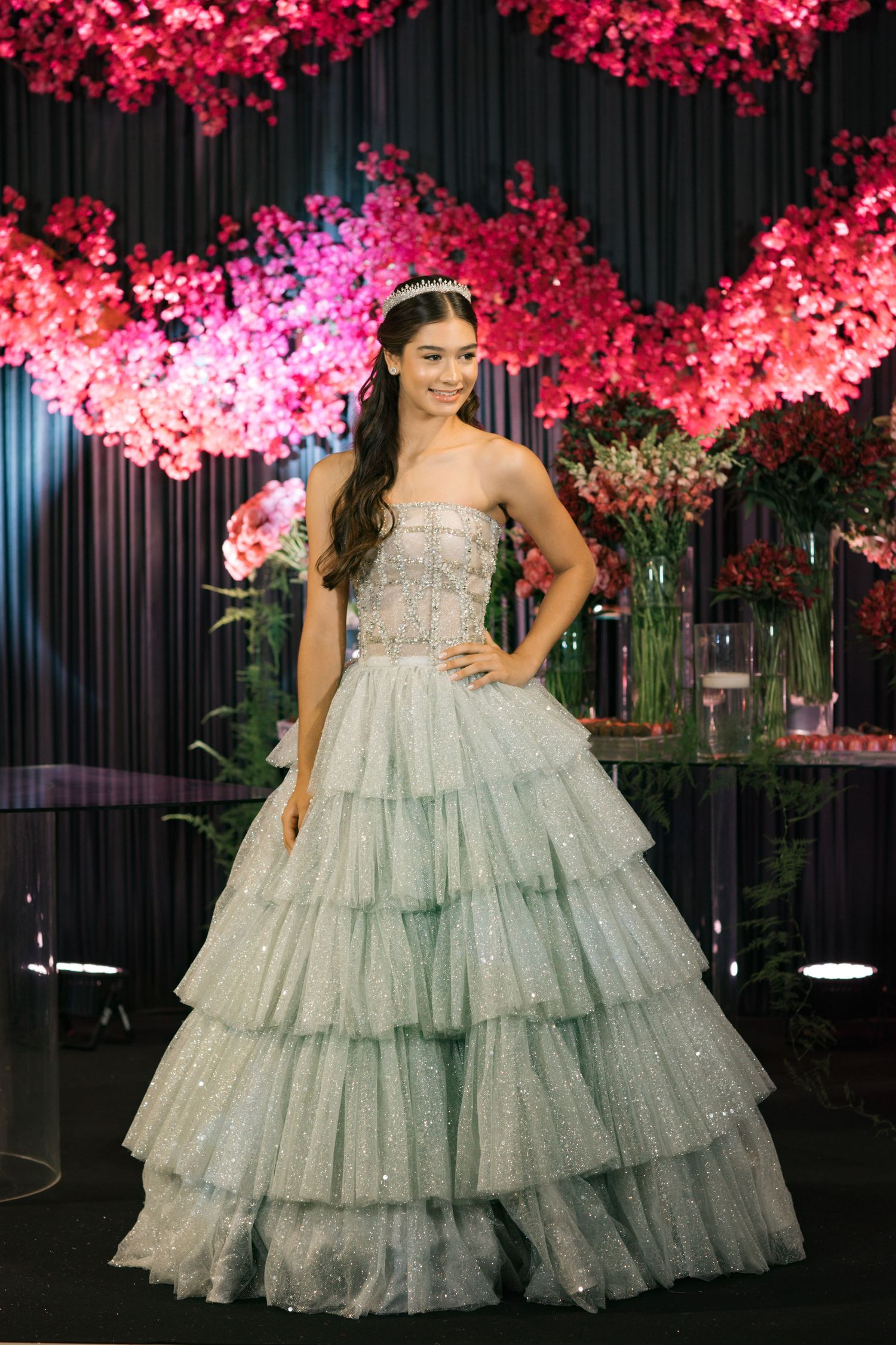 An elegant tiered tulle gown shown against a backdrop of pink cherry blossoms.