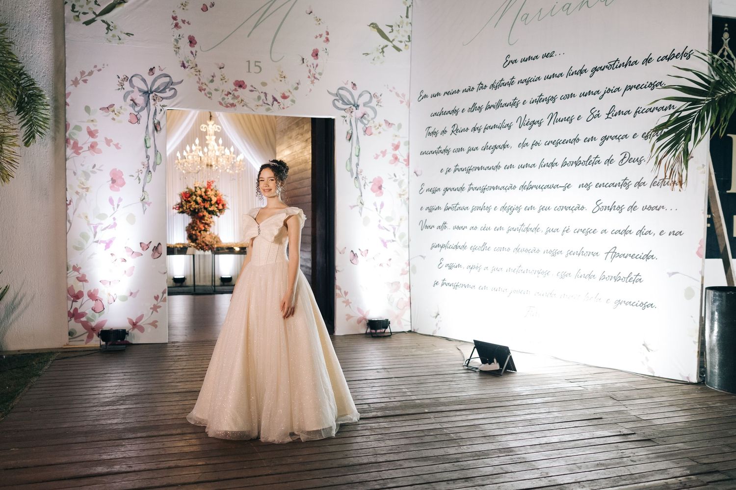 A person in a flowing tulle gown stands in a romantic space with floral wall decorations and handwritten text.