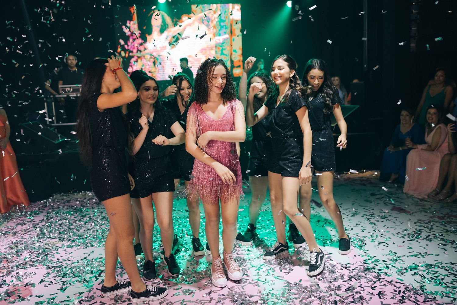 Party scene with confetti and green lighting on dance floor.