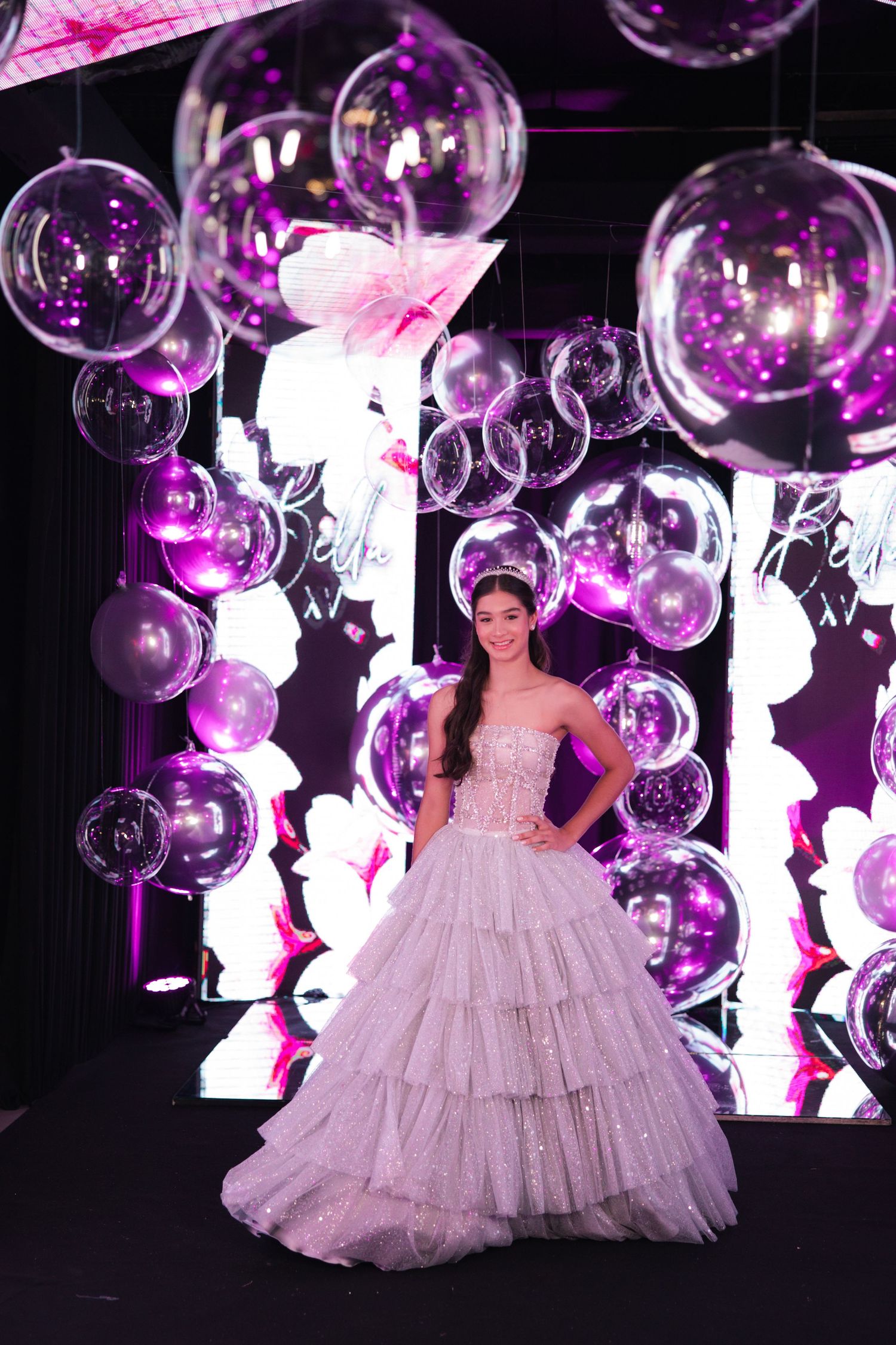 A stunning ballgown is displayed against a backdrop of floating bubbles and pink lighting effects.