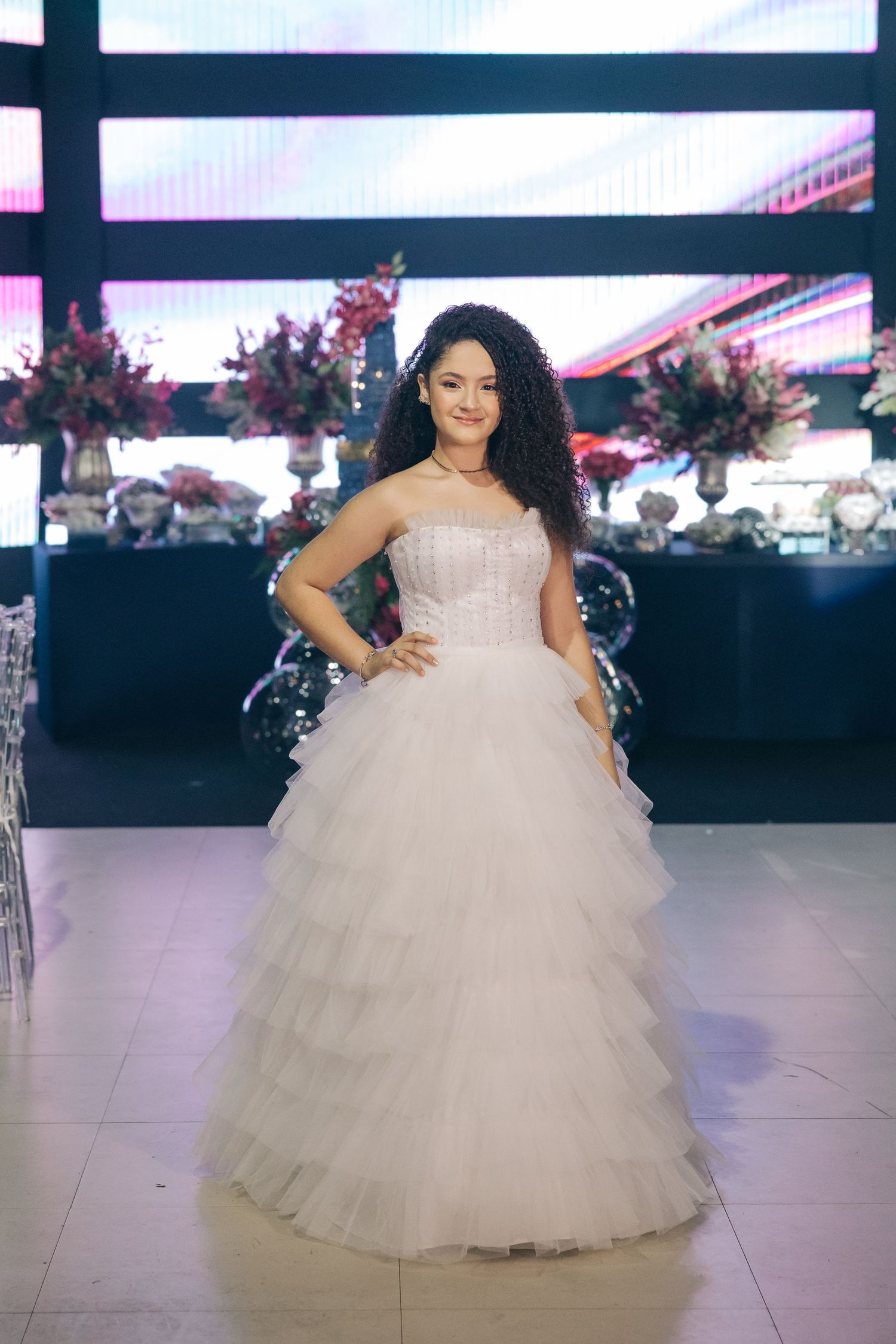 A bride poses in a stunning white strapless ballgown with ruffled tulle skirt in an elegant reception venue.