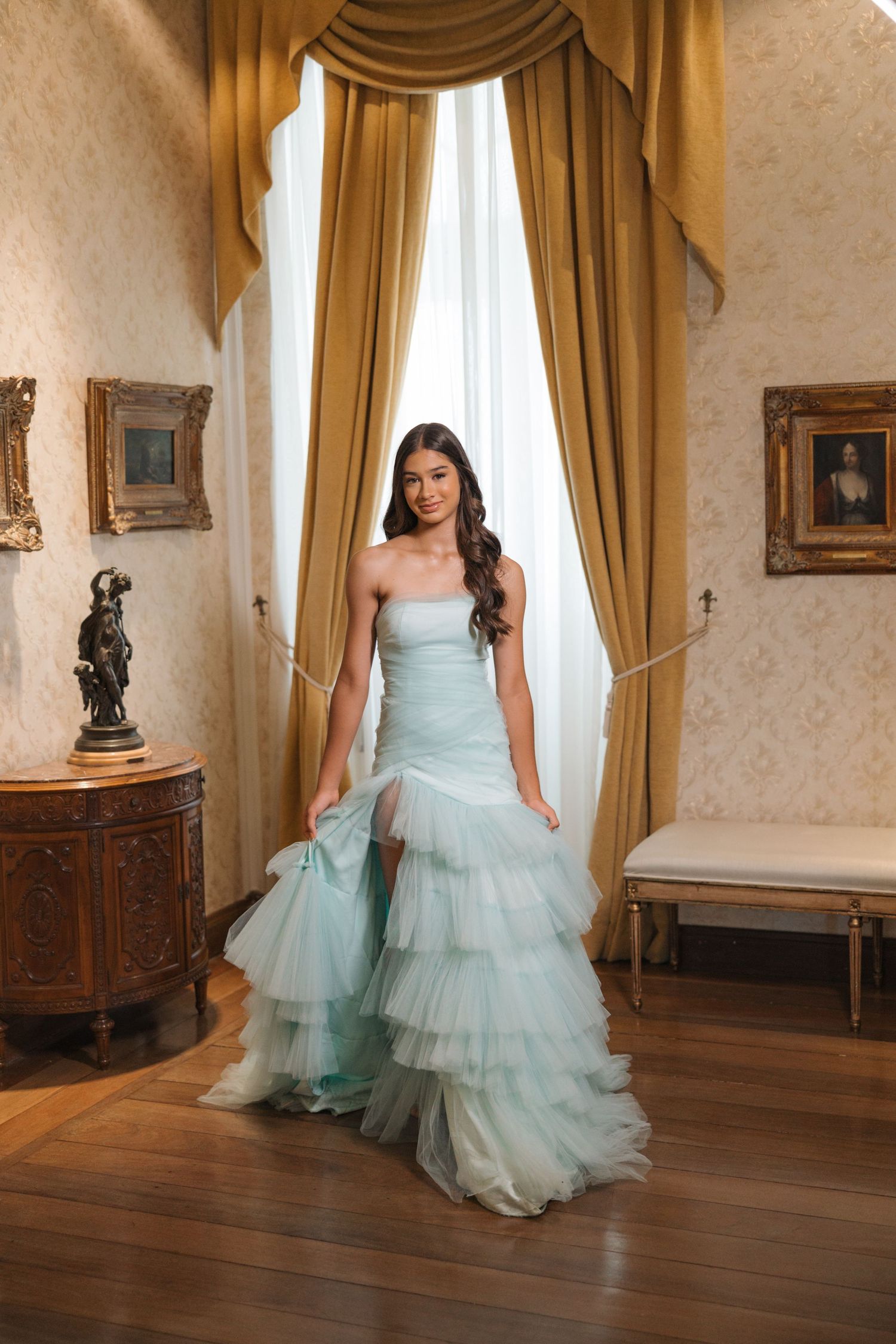 Dreamy mint green layered tulle gown showcased in a classic room with gold curtains and antique furnishings.