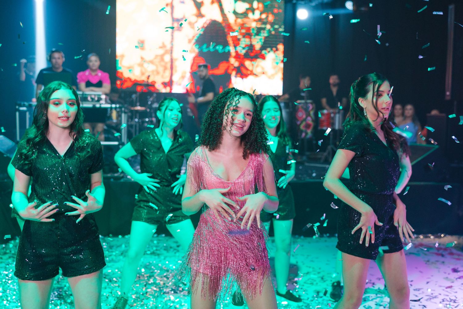 Party scene with dance floor illuminated by colorful lights and confetti during celebration.