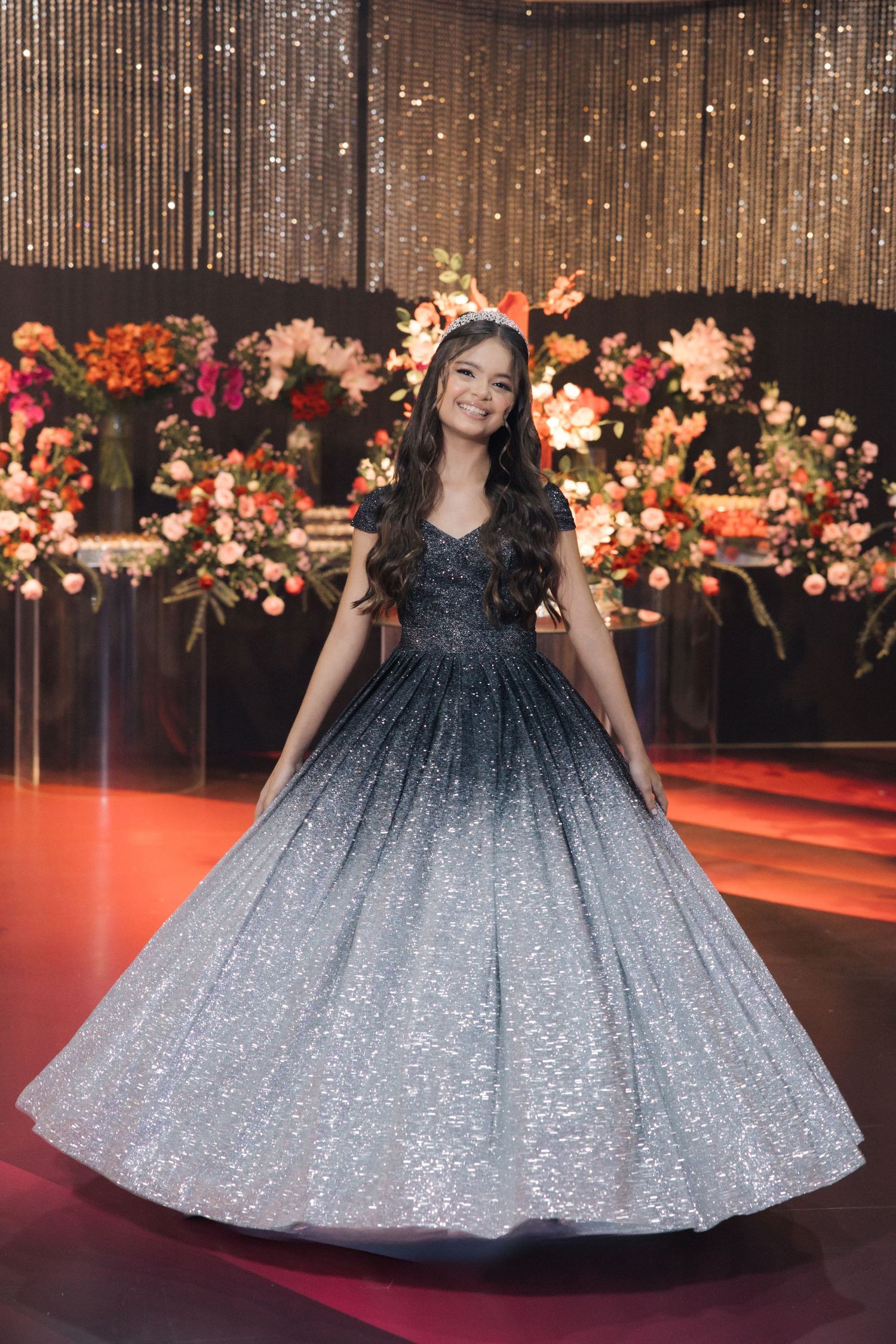 A stunning black and silver glitter ball gown showcased against a floral backdrop with string lights.