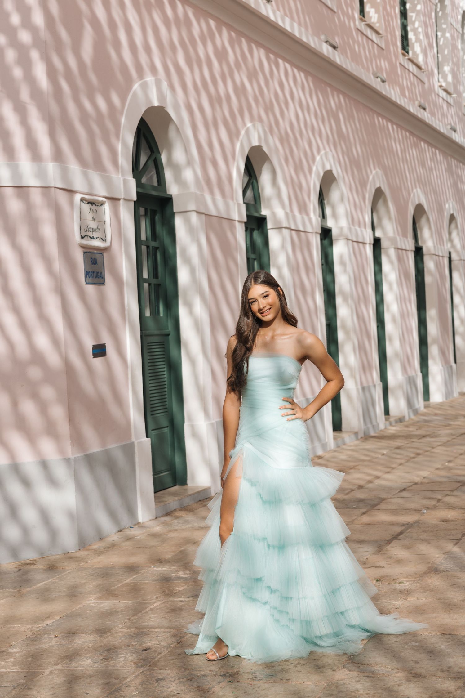 Elegant mint-colored tulle gown photographed against a pink wall with arched doorways and dappled shadows.
