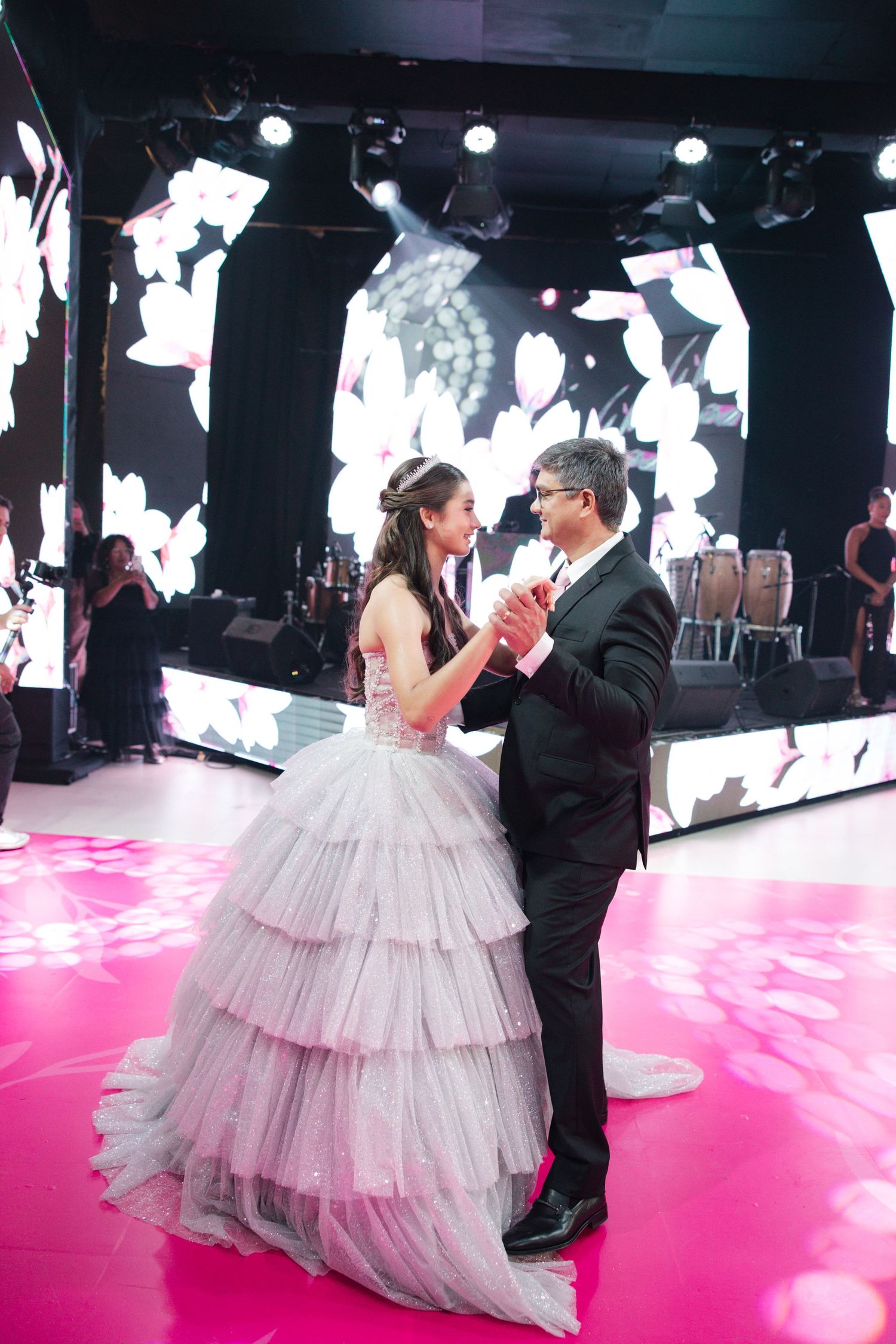 A romantic first dance on a pink-lit dance floor with elegant white video wall backdrop.