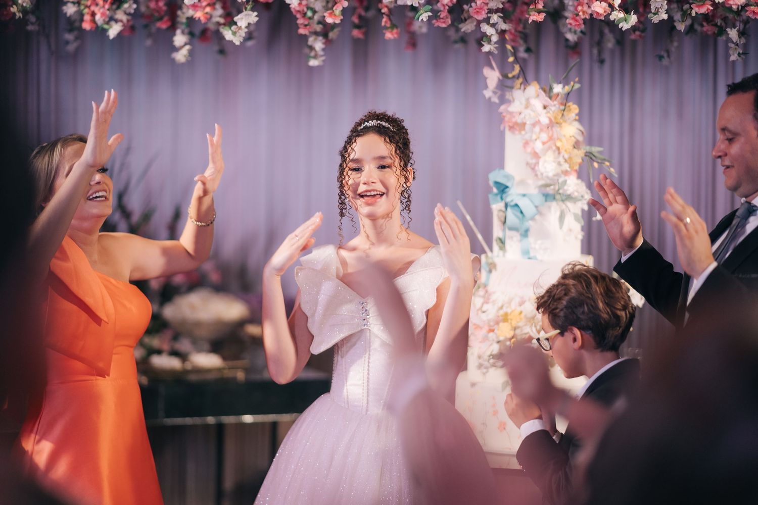 Wedding celebration with guests clapping and dancing around the bride in a white gown.