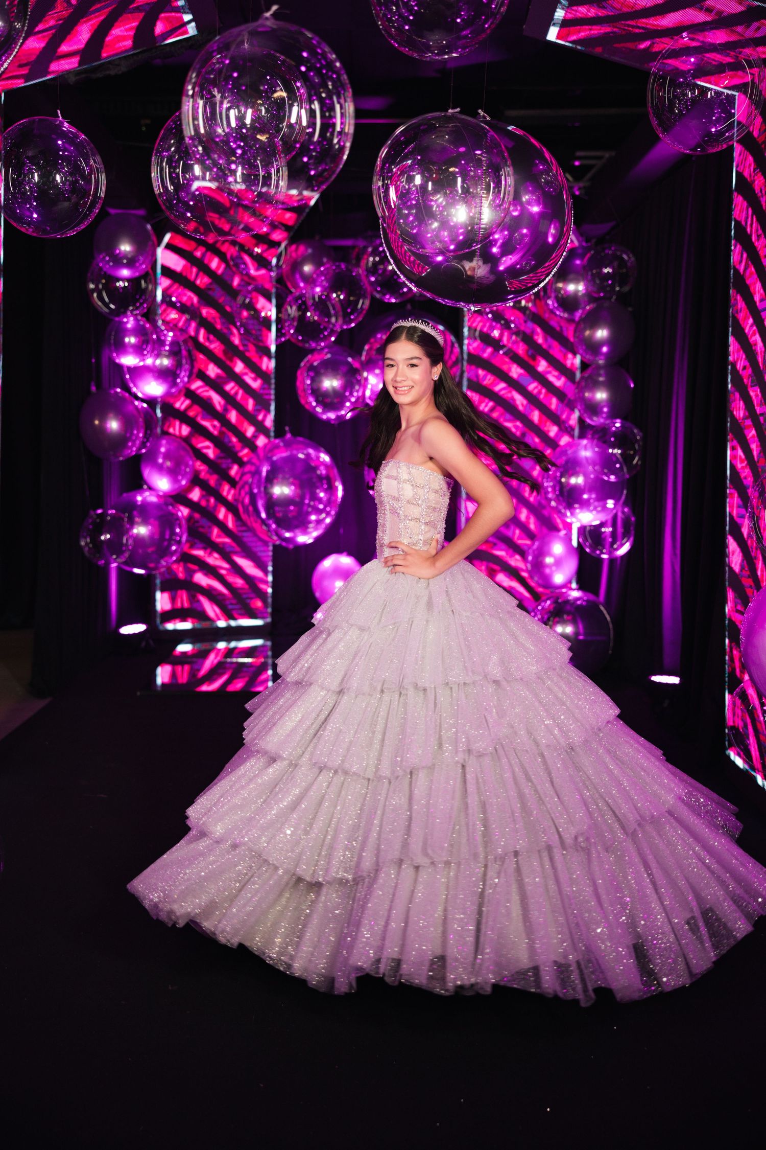 An elegant gown against a backdrop of purple disco balls and dramatic lighting at a formal celebration.