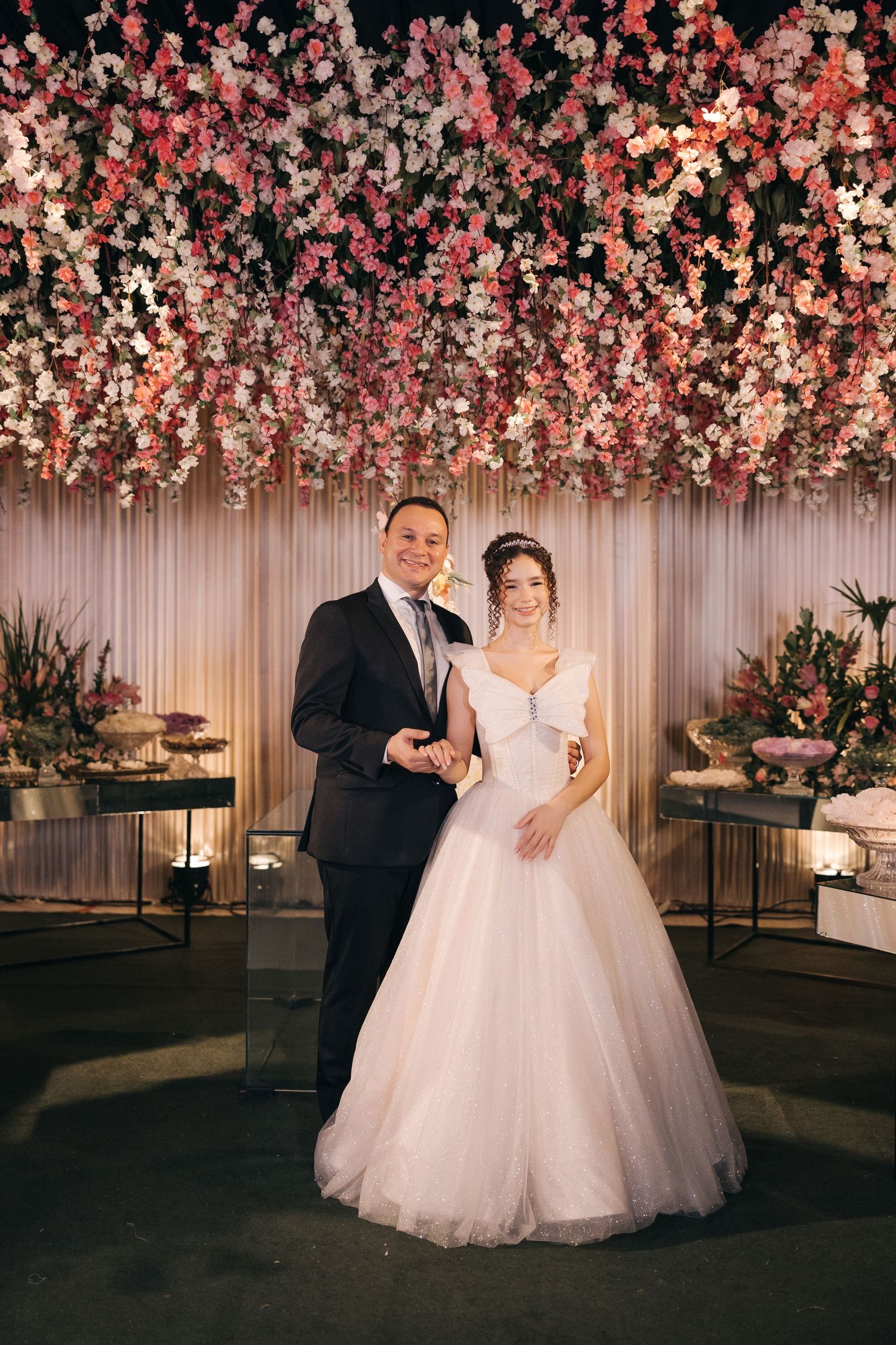 A romantic wedding scene under a canopy of pink cherry blossoms with elegant table settings.