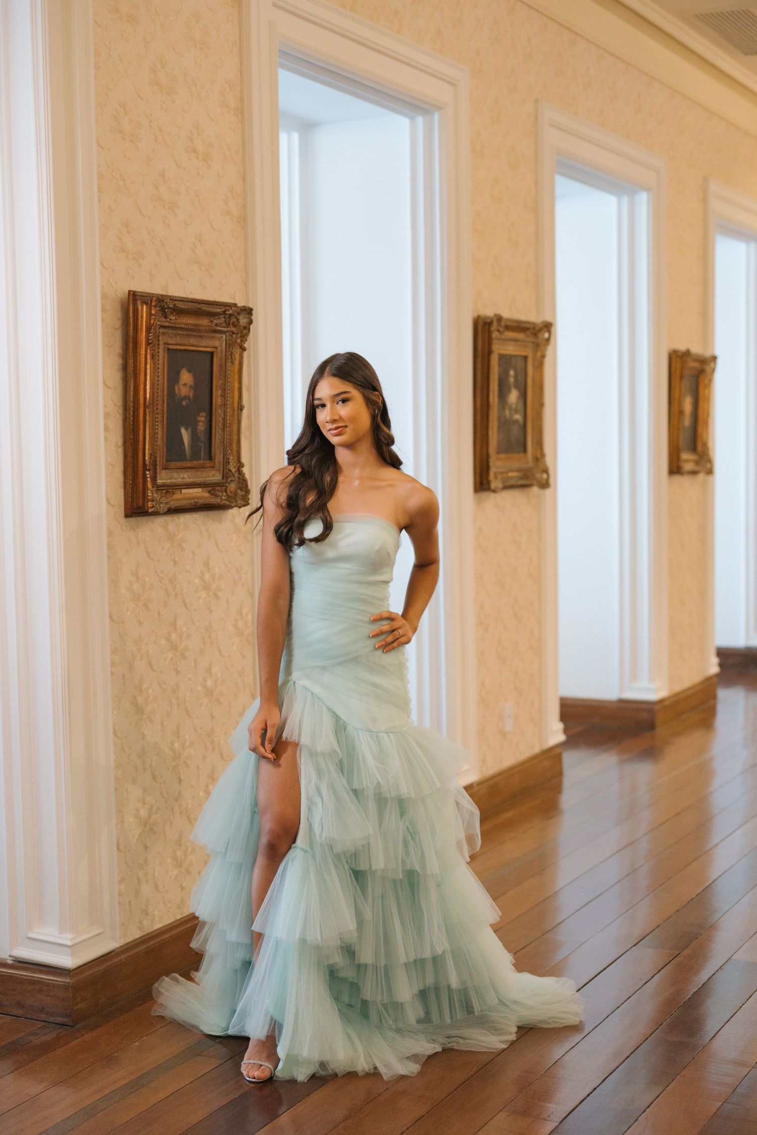 A strapless mint green gown with layered tulle skirt showcased in an elegant interior with hardwood floors.