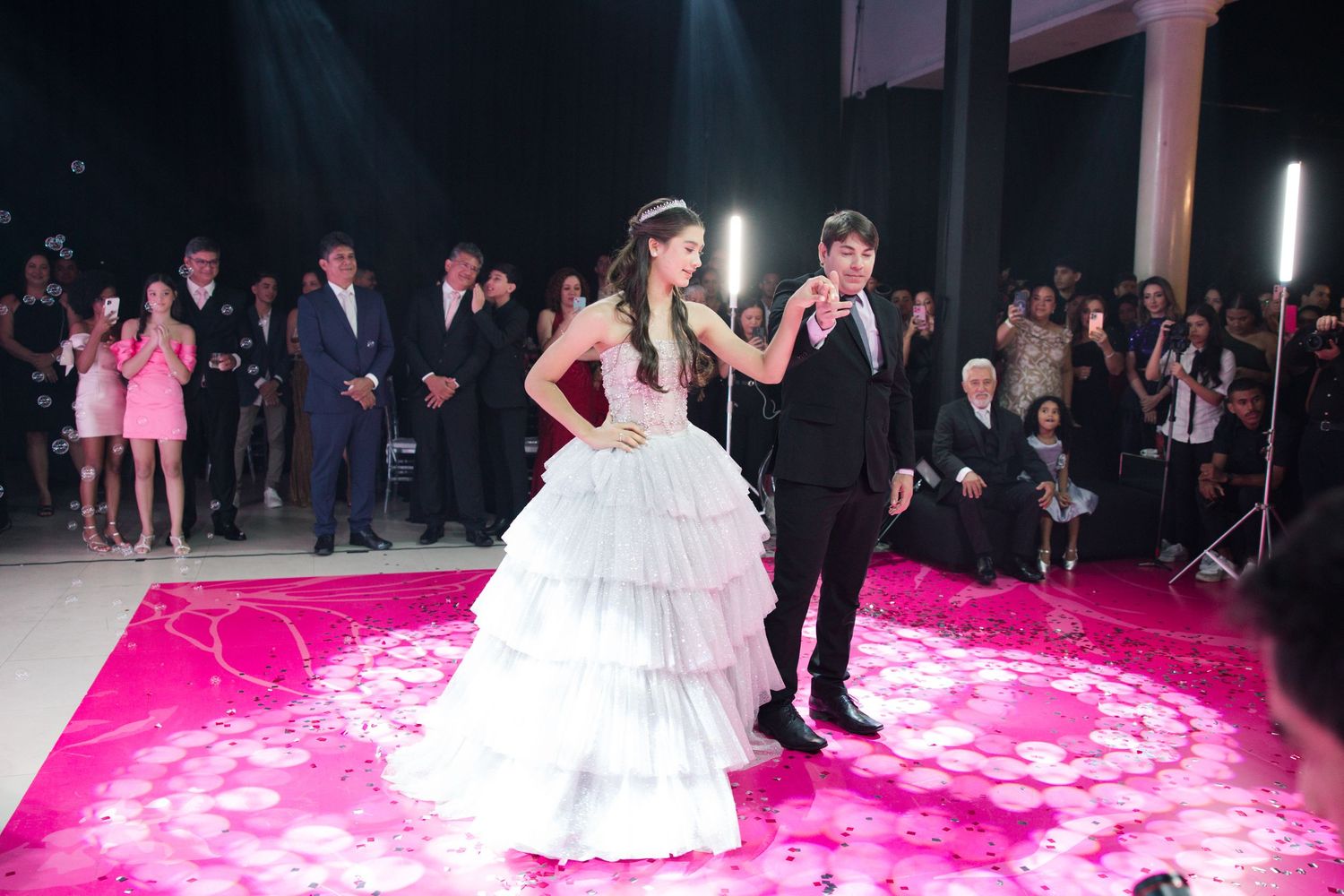 Performers dance on an illuminated pink floor during an elegant celebration.