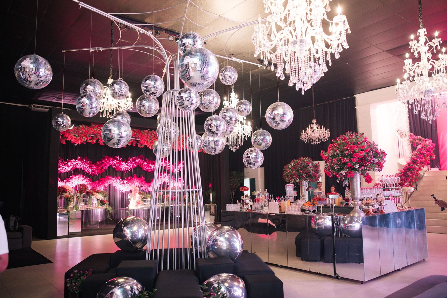 Modern event venue featuring hanging disco balls, crystal chandeliers, and contemporary seating arrangements.