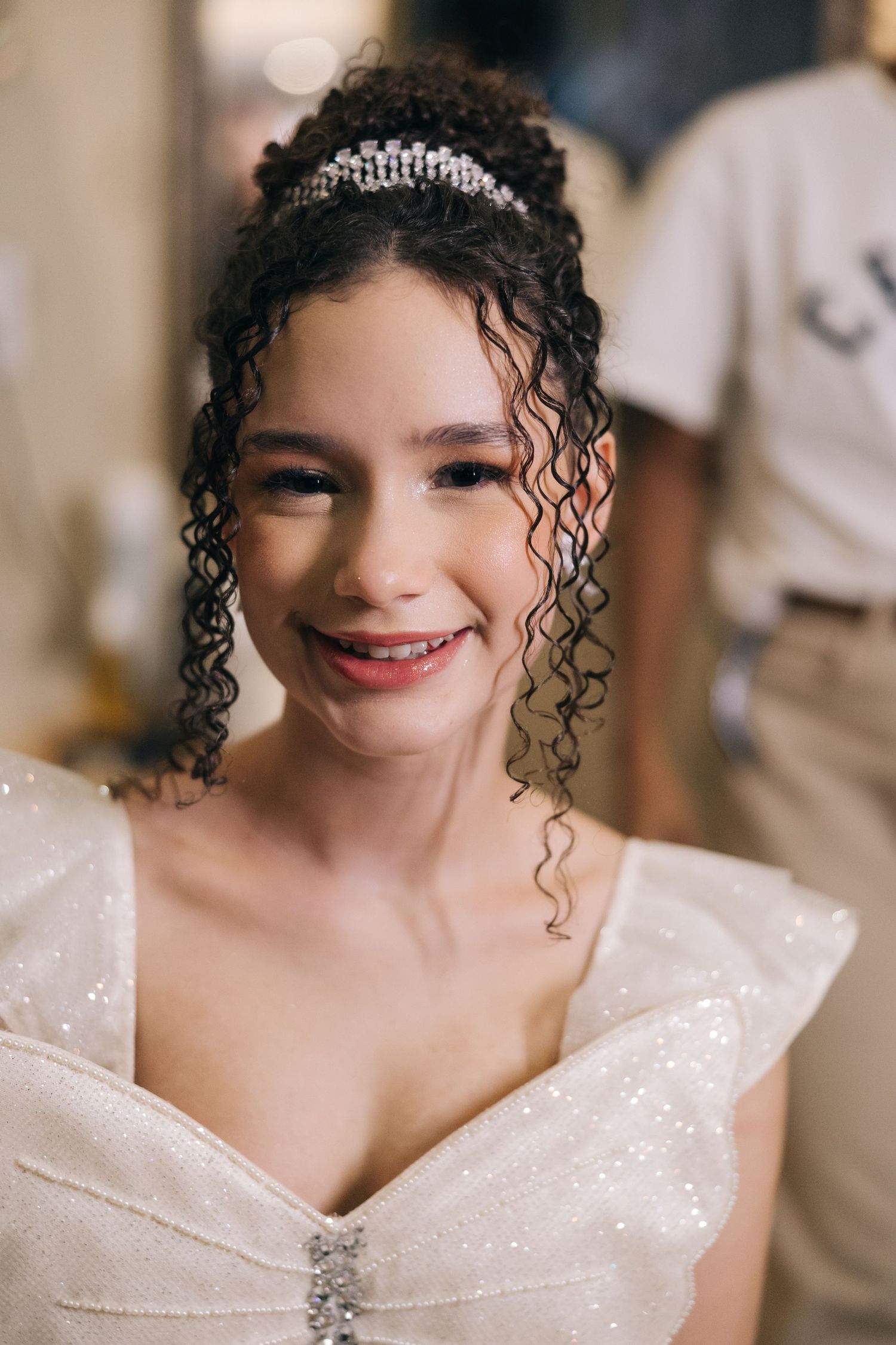 A sparkling white gown adorned with delicate details and a crystal tiara creates an elegant bridal look.