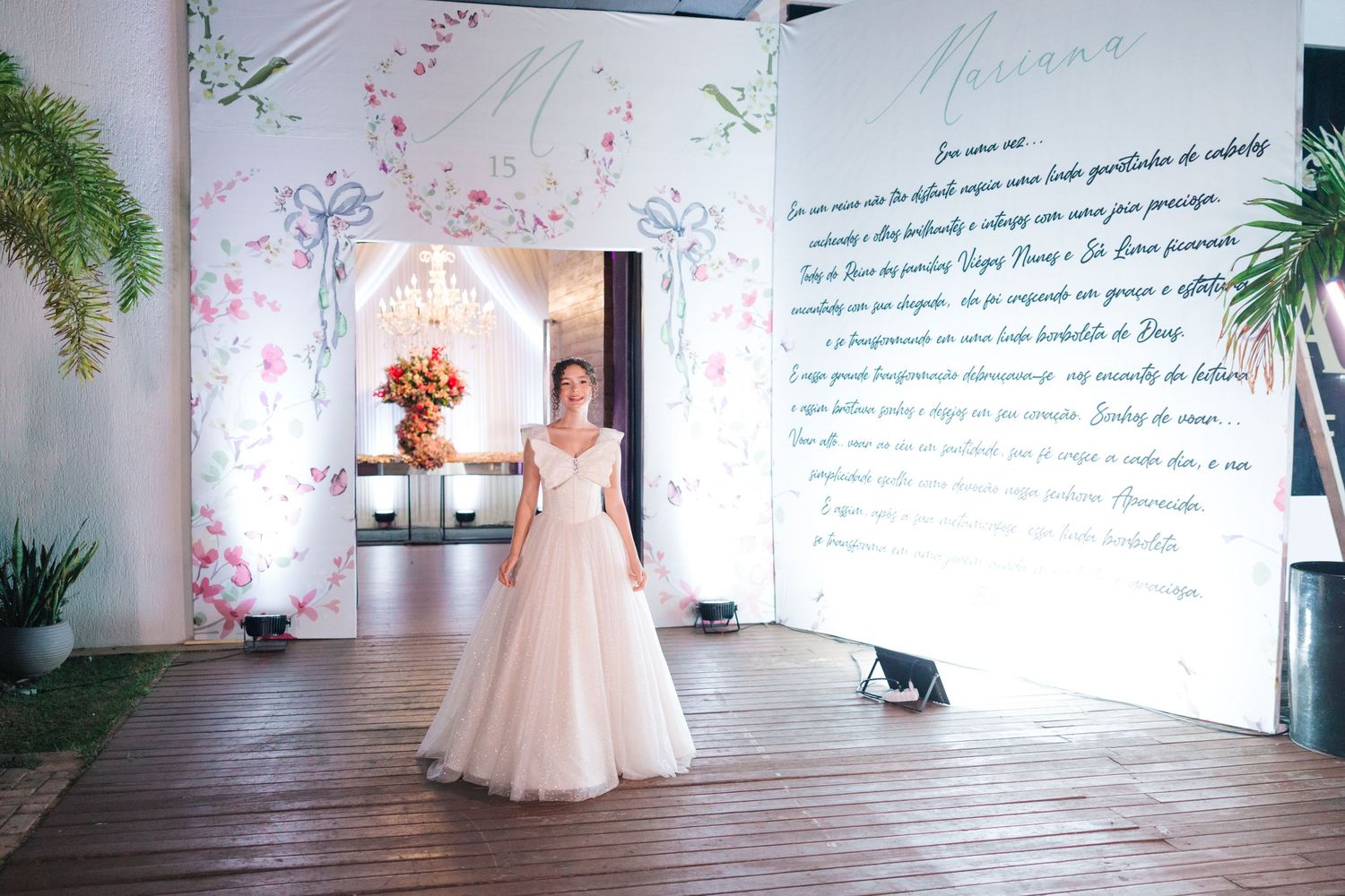 Elegant ballgown in a light pink hue stands in a modern venue with floral decor and handwritten wall text.
