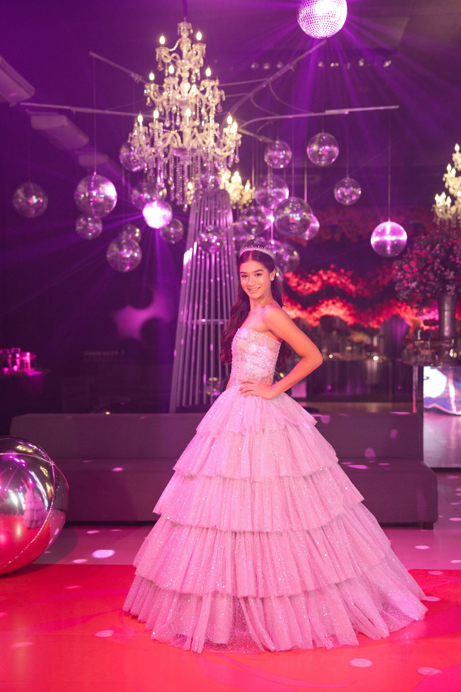 Luxurious ballroom setting with crystal chandeliers and disco balls casting pink and purple ambient lighting.