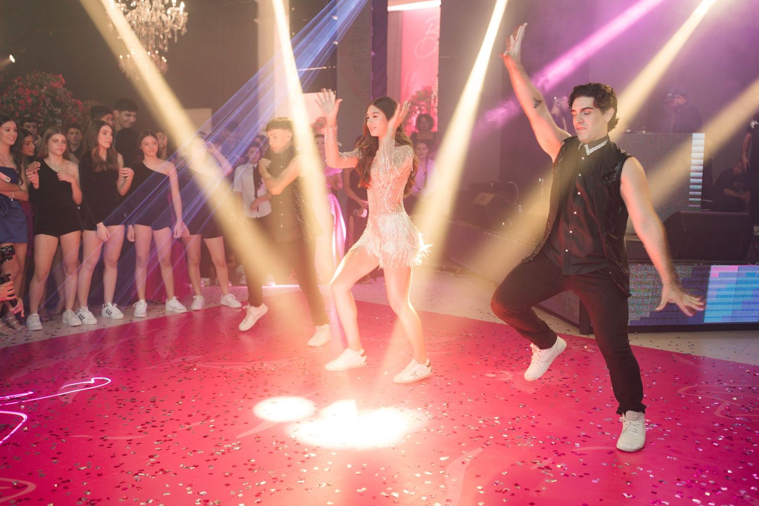 Dynamic dance performance with dramatic spotlight effects and confetti on red-lit stage.